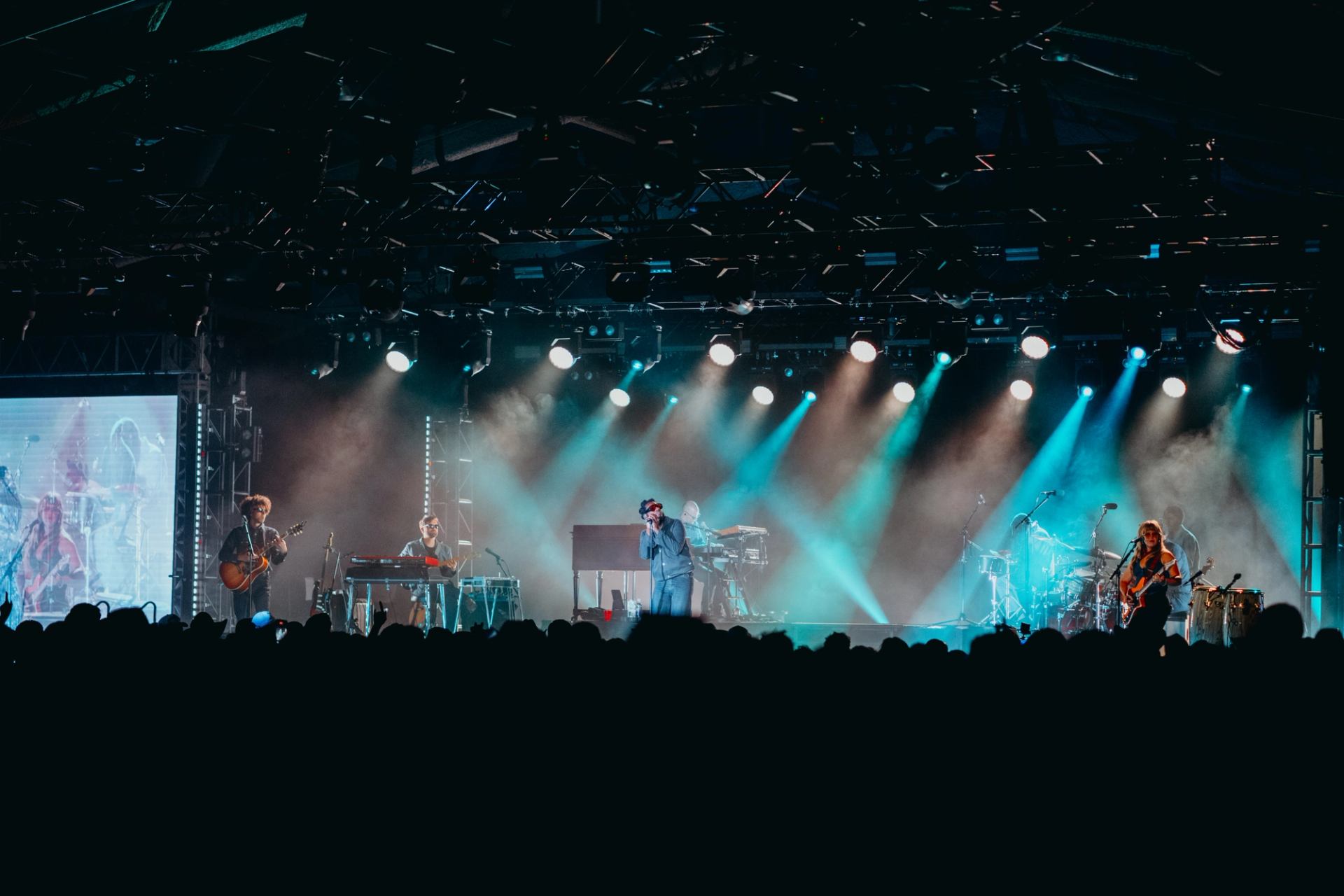Concert at Spruce Meadows with band performing on a lit stage, colorful lights, and a crowd watching below.
