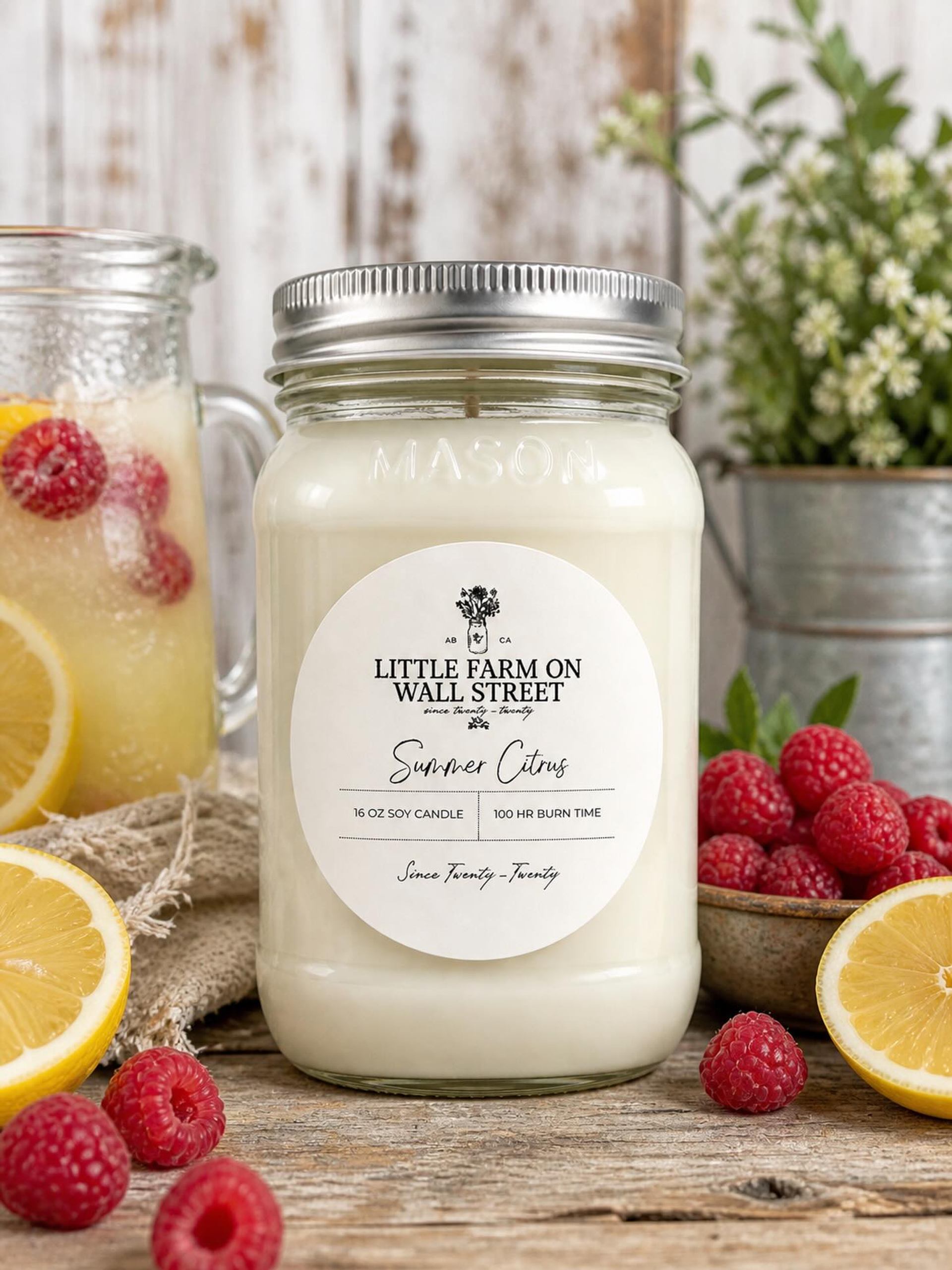 Soy candle in mason jar with Summer Citrus label beside lemons, raspberries and lemonade.