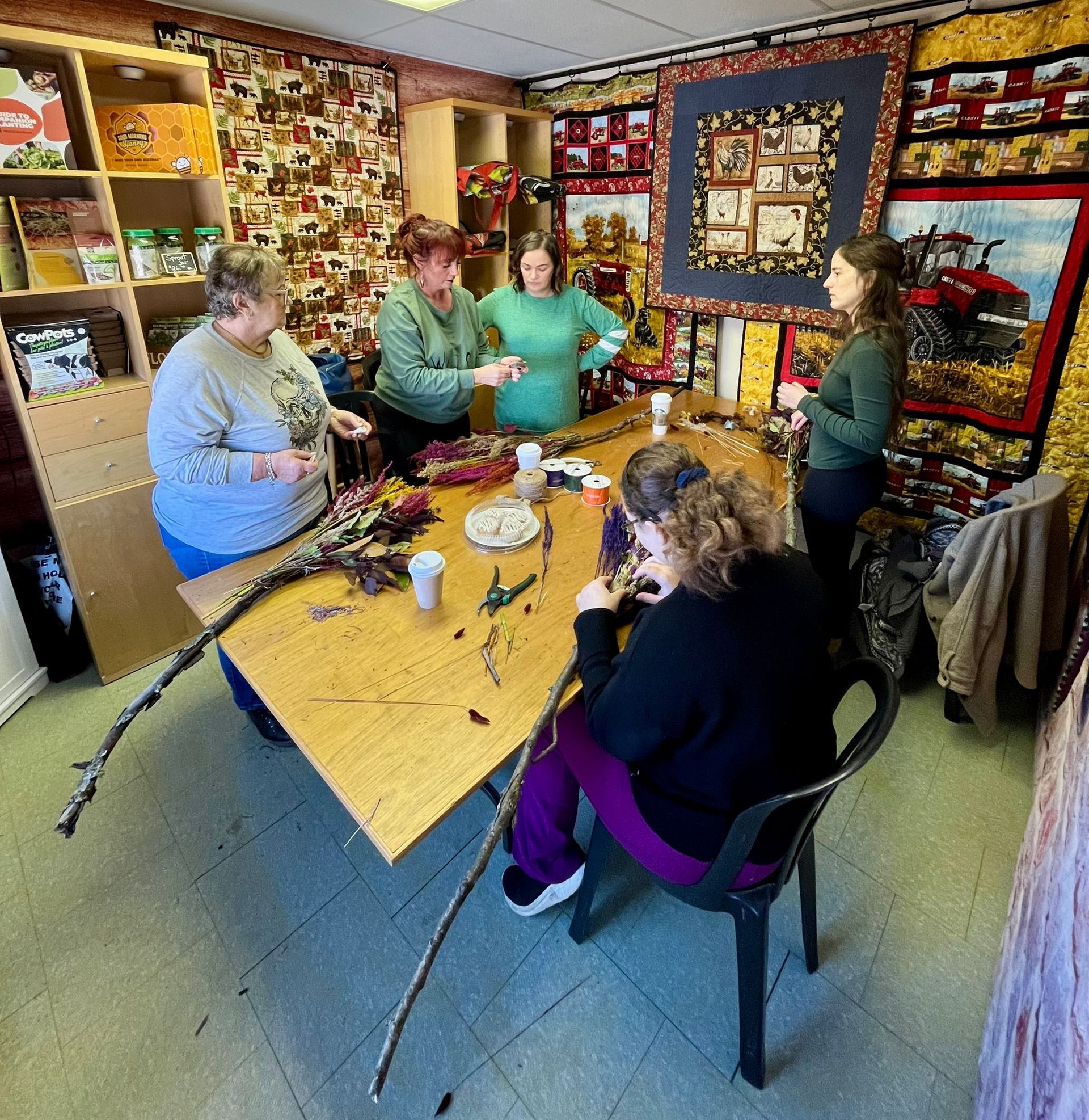 Group gathered around a table making crafts in a cozy, quilt-decorated room.