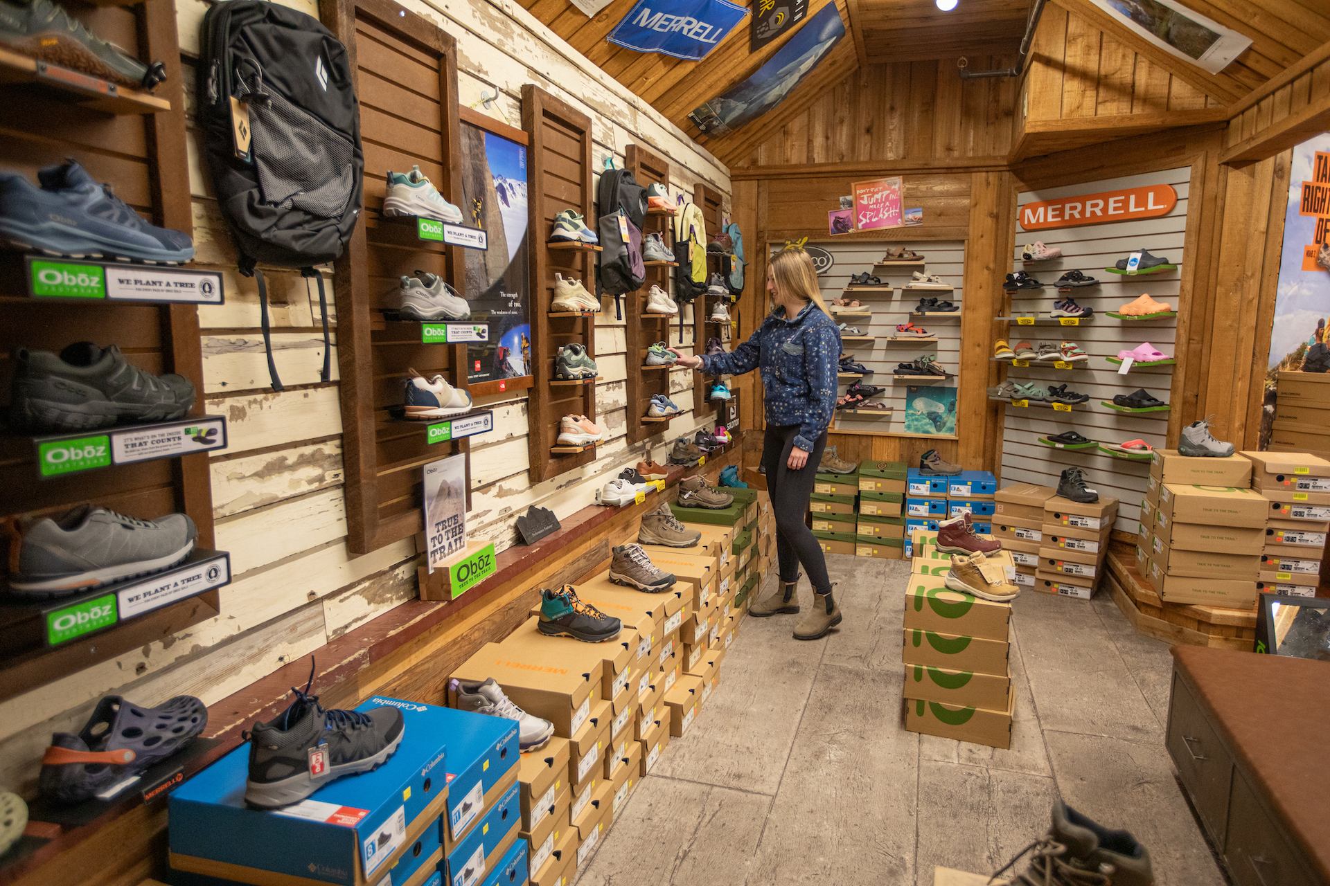 Shopper browses hiking shoes in Tamarack’s rustic gear store.