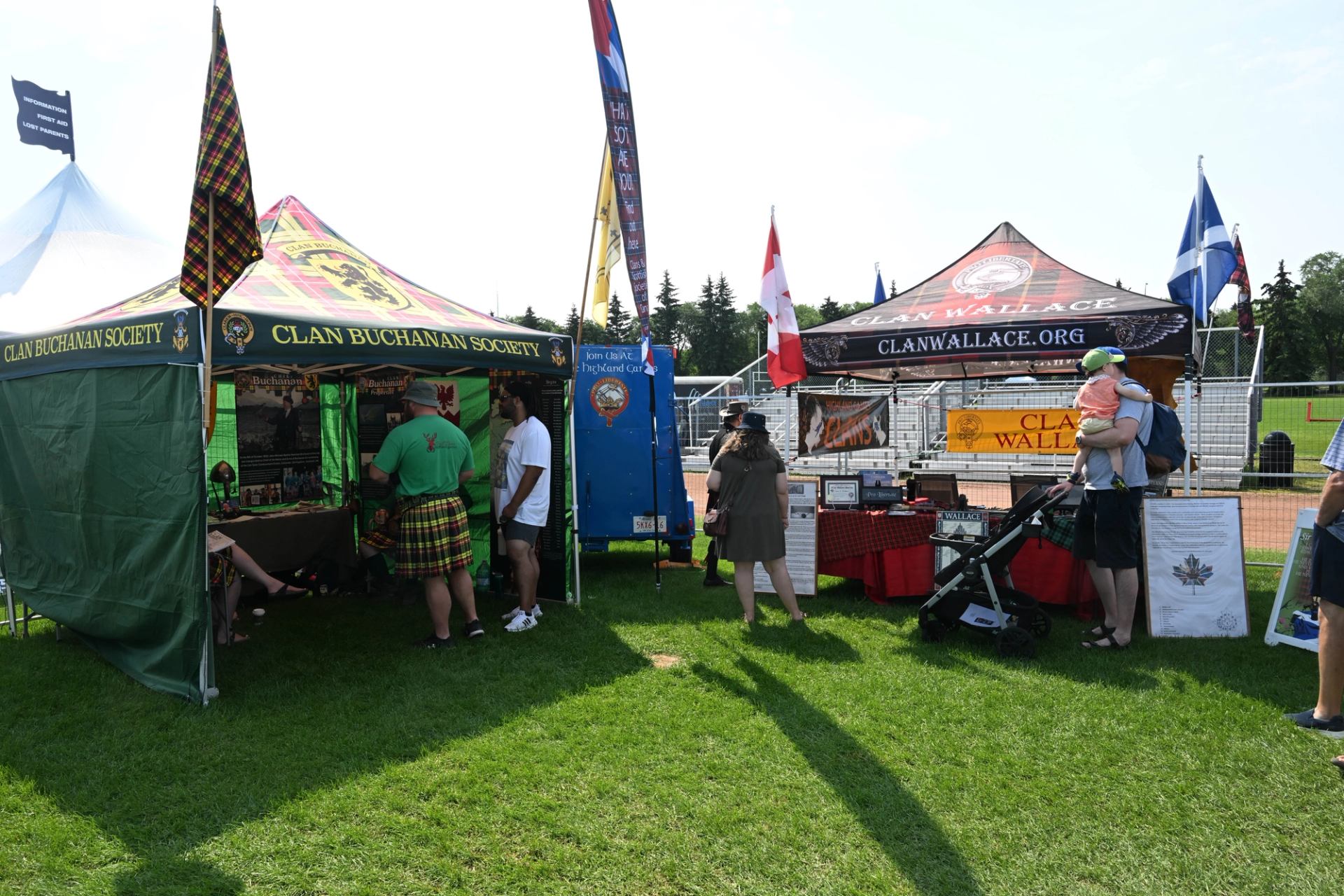 Clan tents and people in kilts at outdoor Scottish festival.