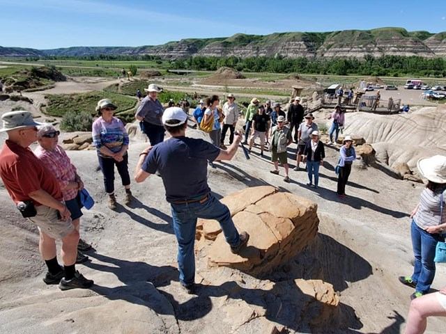Tour guide speaking to group near large rock in Drumheller Badlands