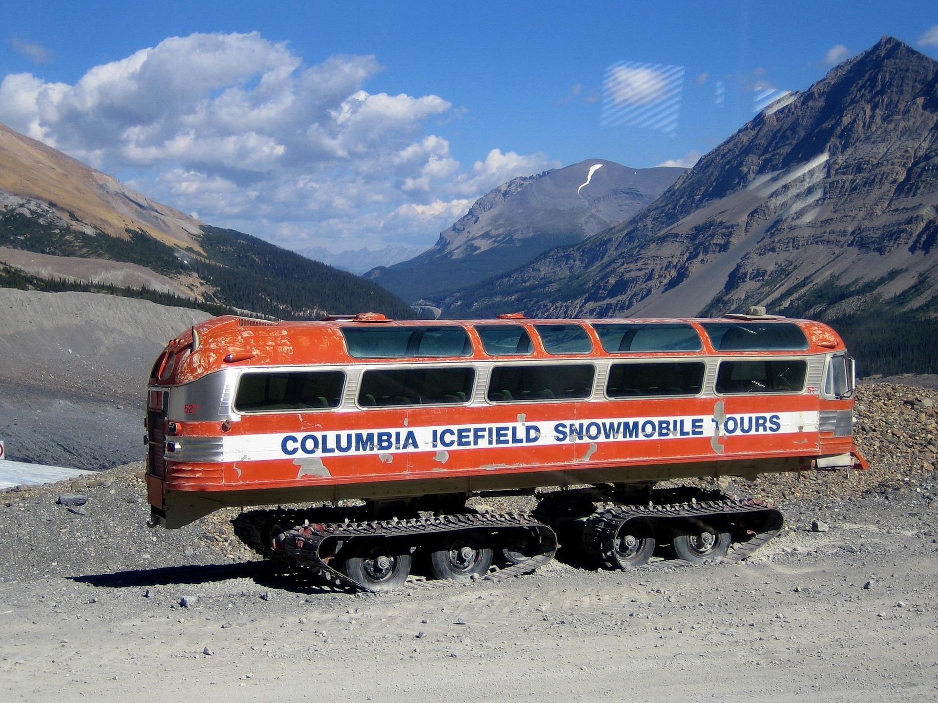 Columbia Icefield Snowmobile Tours vehicle with tracks parked on rocky mountain terrain.