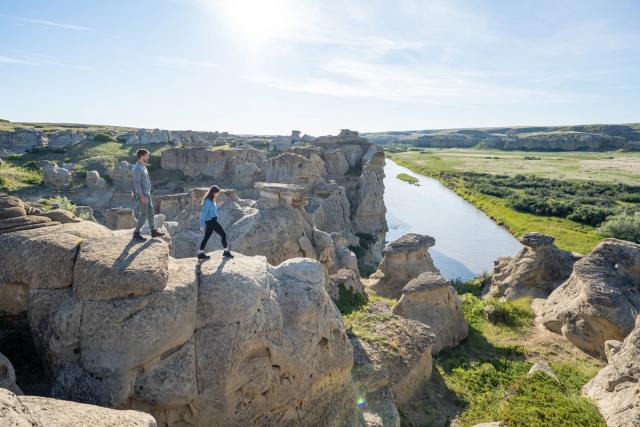 A couple exploring and hiking along the rock ridge at Writing-on-Stone Provincial Park in Southern Alberta.