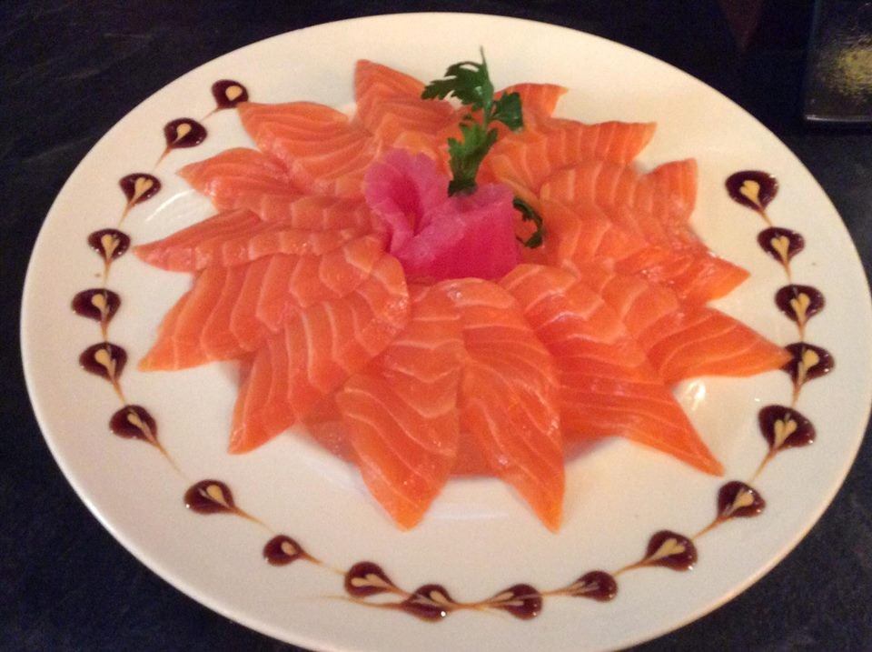 Thinly sliced salmon sashimi arranged in a flower pattern with garnish