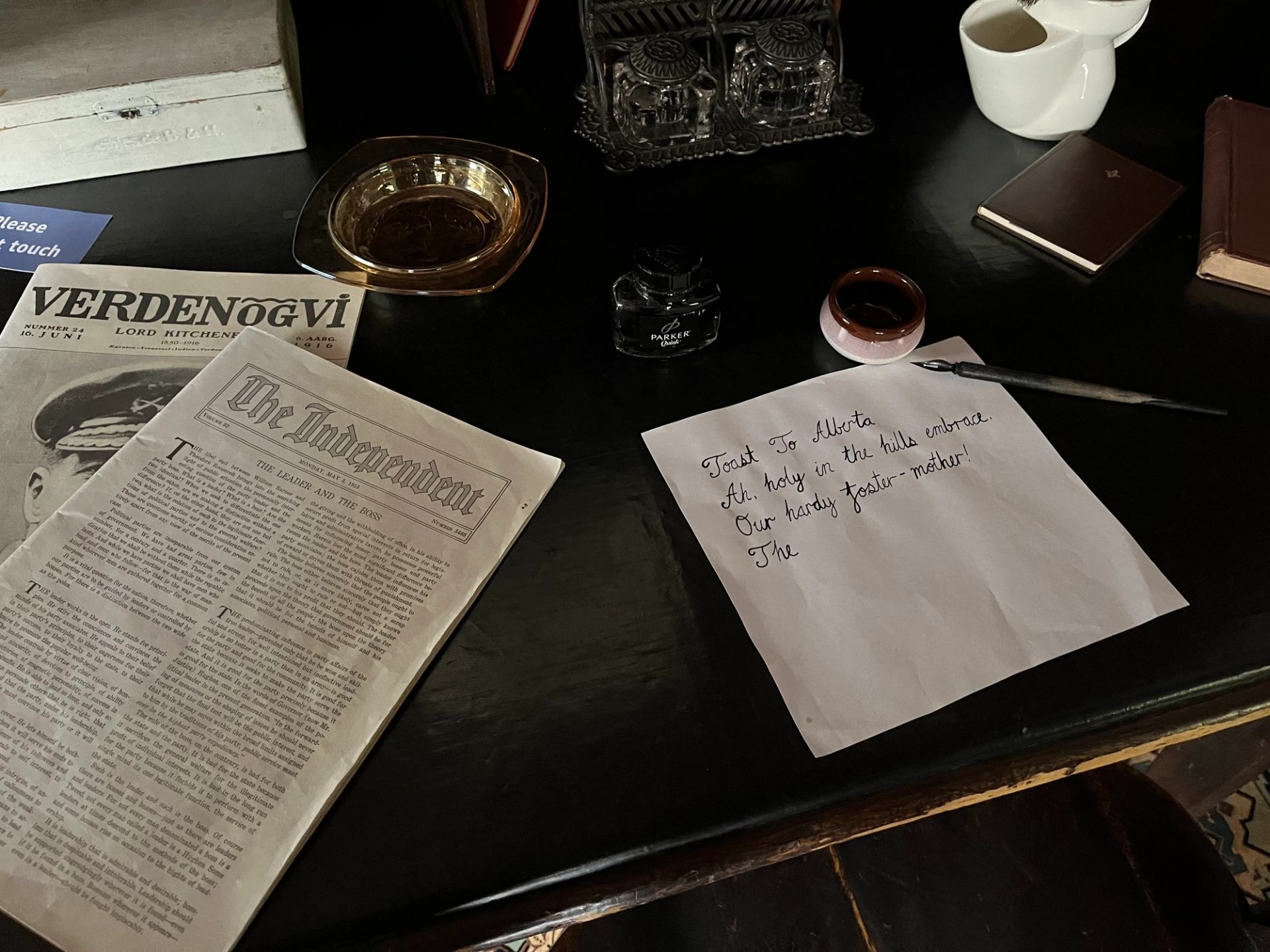 A desk with newspaper clippings and a written poem on it.