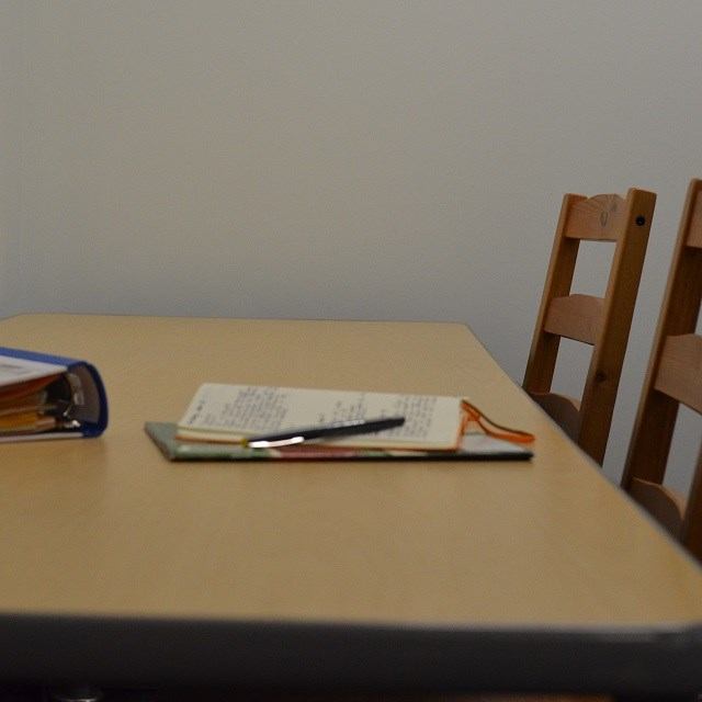 Meeting table with books, notebook, and chairs inside a library.