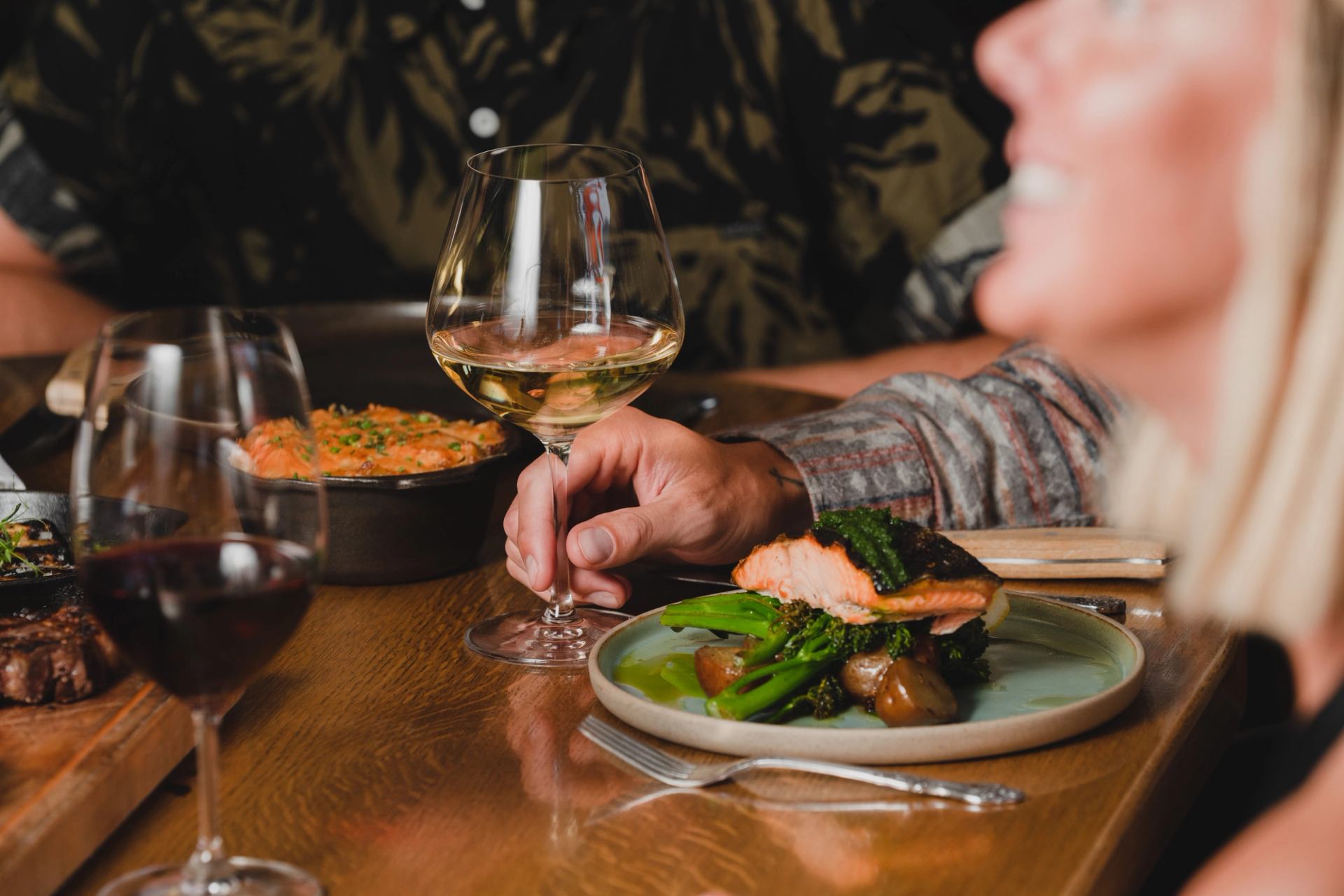 A table with wine, salmon, and steak dishes served at Chuck’s Steakhouse & Patio.