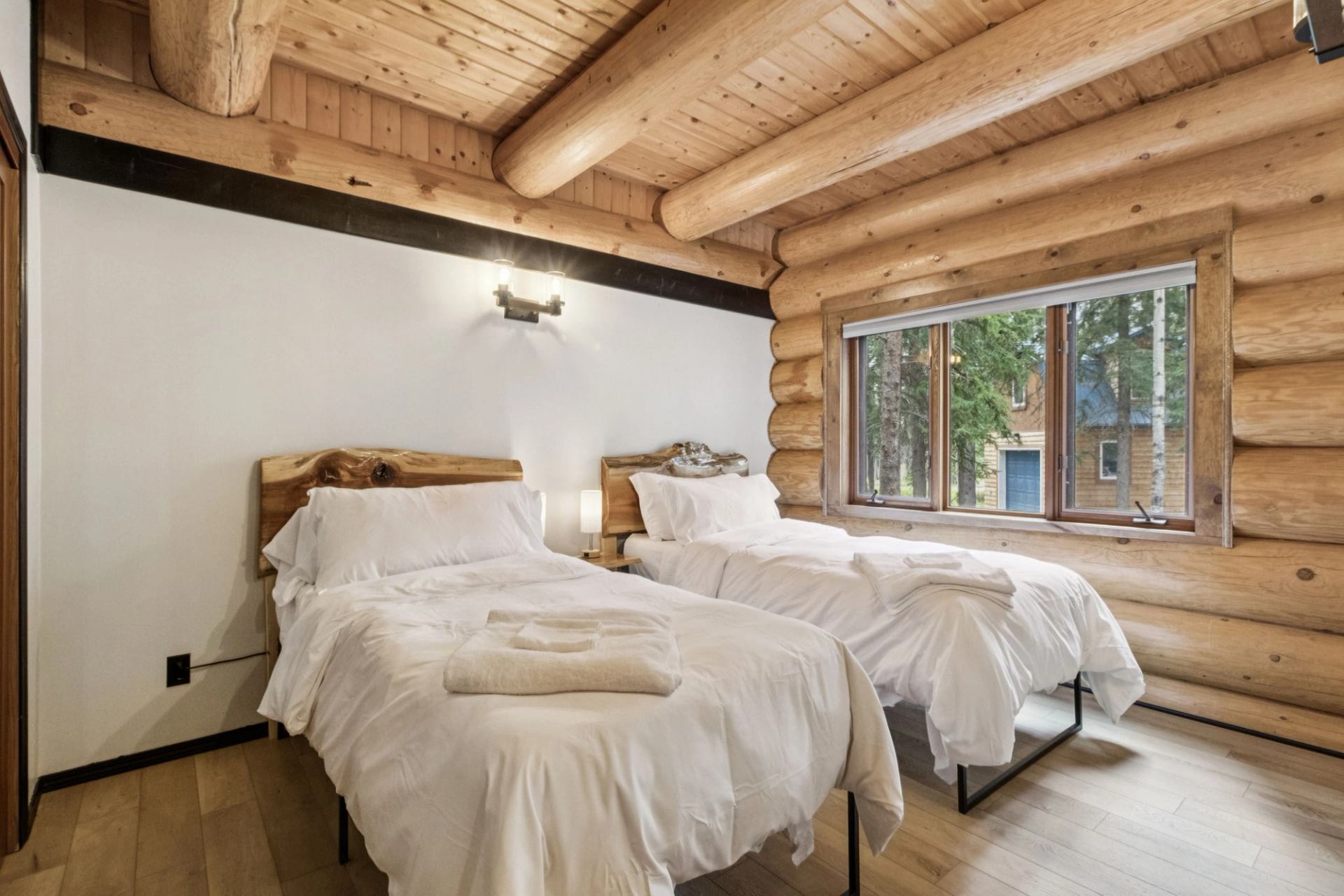 Twin beds in a rustic log cabin bedroom with natural light.