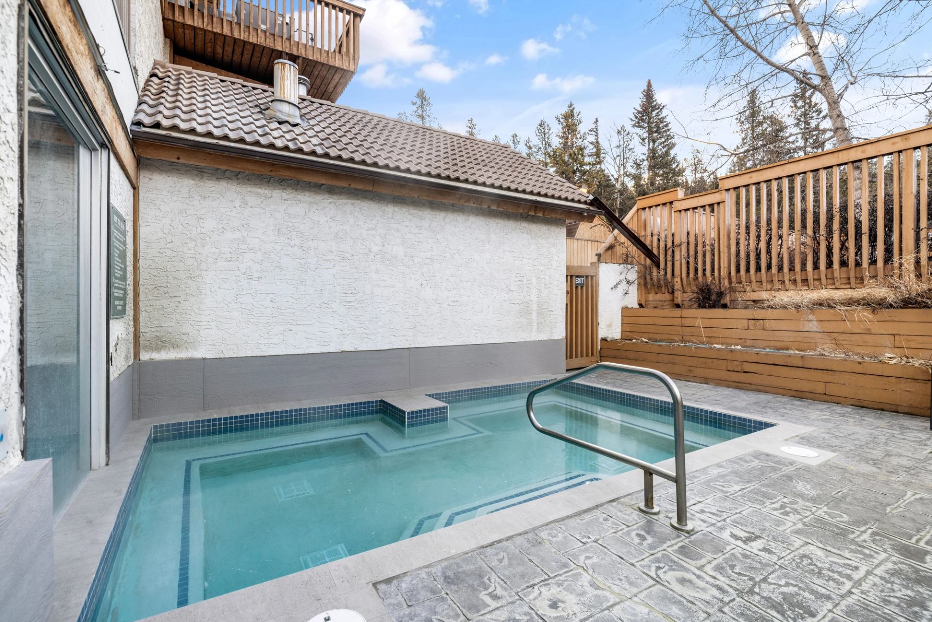 Outdoor hot tub with a brown fence on the right side.