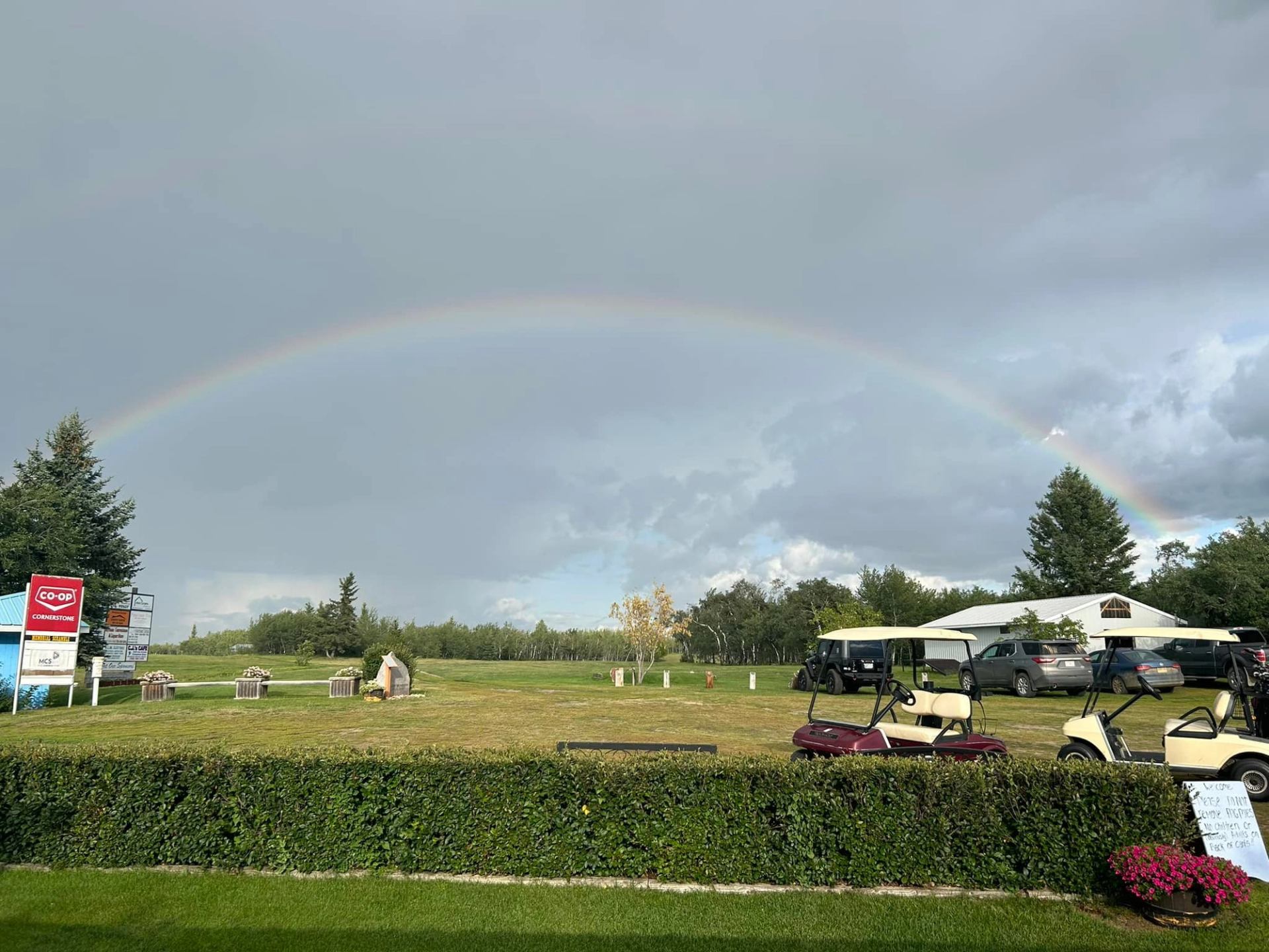 Vibrant rainbow arching over golf carts and clubhouse with lush greenery