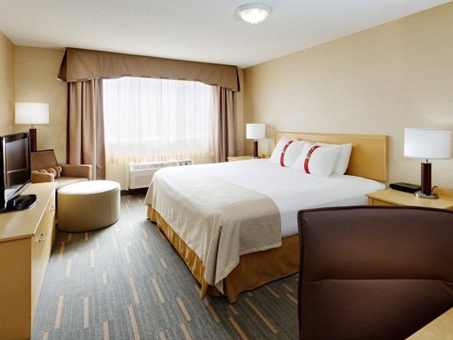Bright hotel room with king bed, TV, and seating area at Holiday Inn.