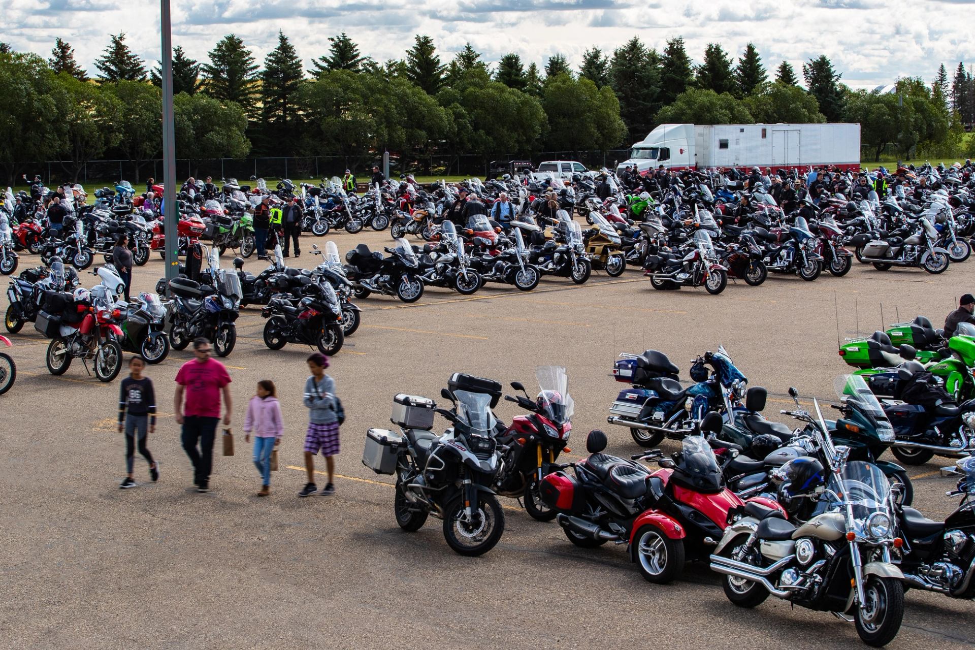 Motorcycles parked in rows at a ride event, with people walking between bikes.