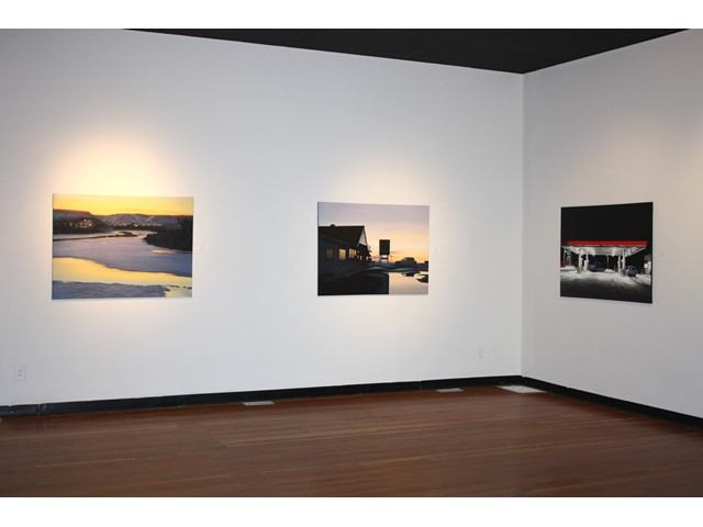 A gallery space with a series of artwork on the walls featuring portraits and scenes.