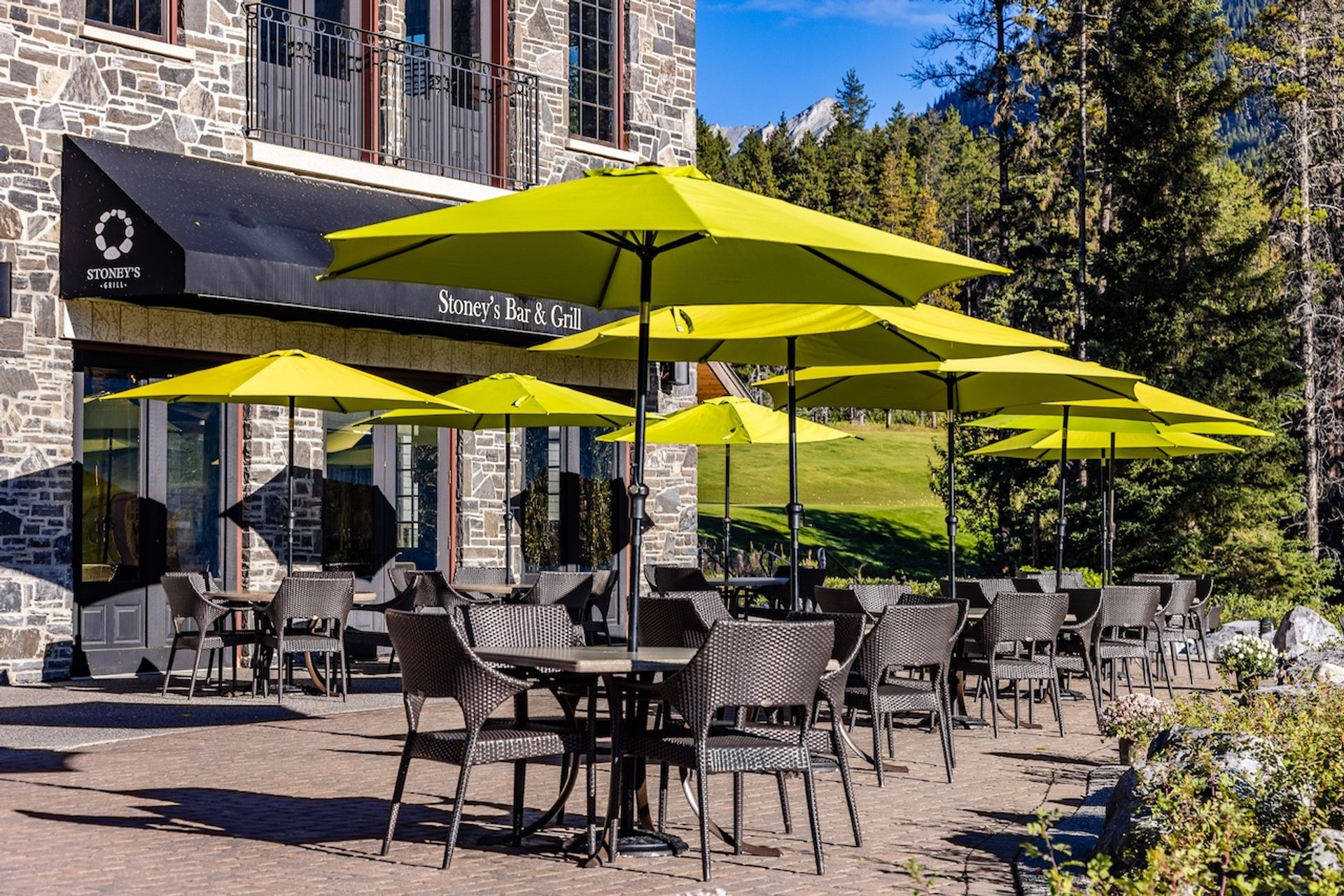 Outdoor dining area with bright yellow umbrellas beside a stone building