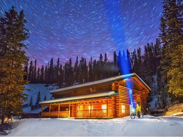 Man with a fatbike outside of Sundance Lodge at night with starry skies.