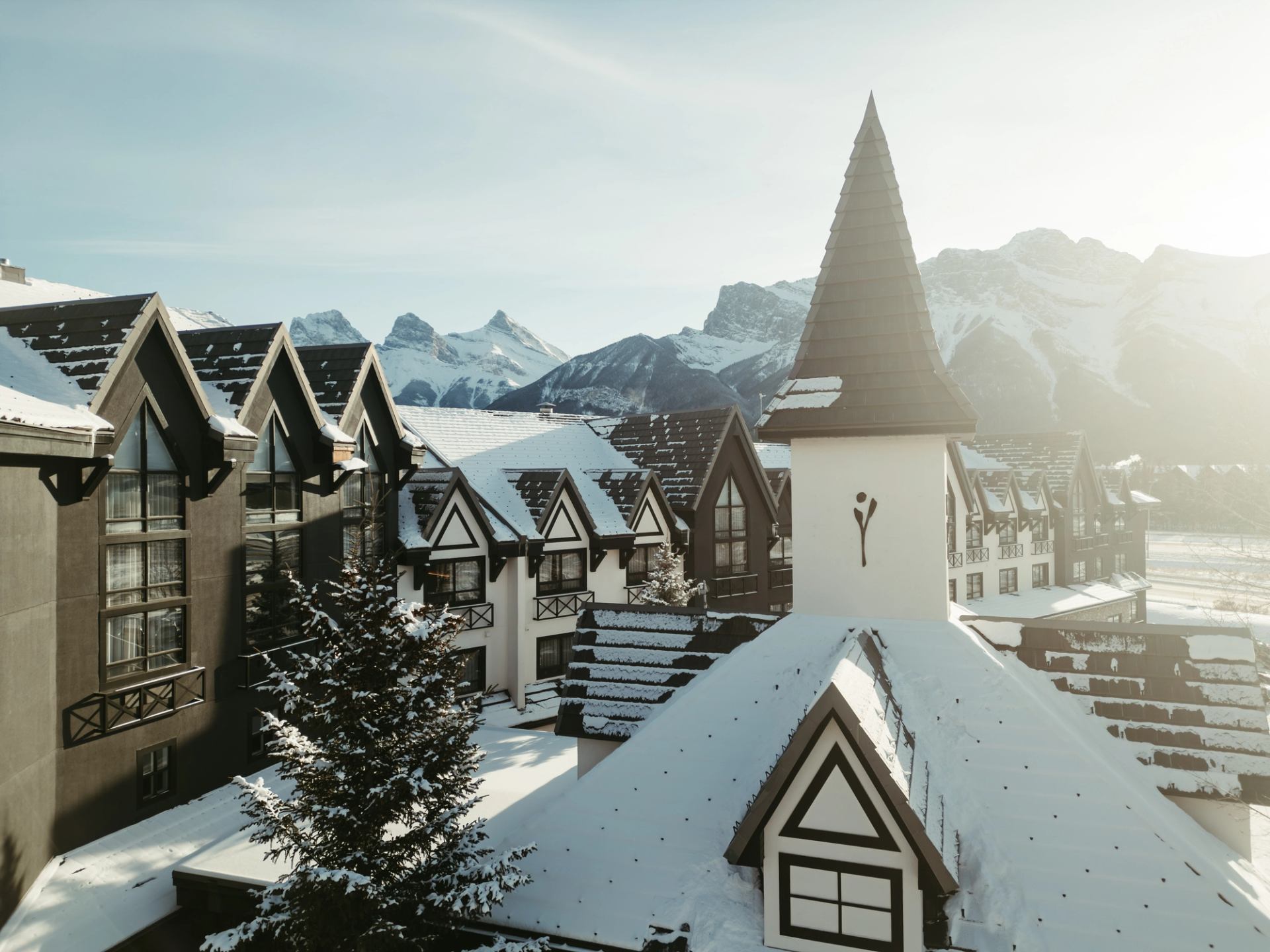 Snow-covered alpine-style hotel buildings with pointed roofs against distant mountain peaks