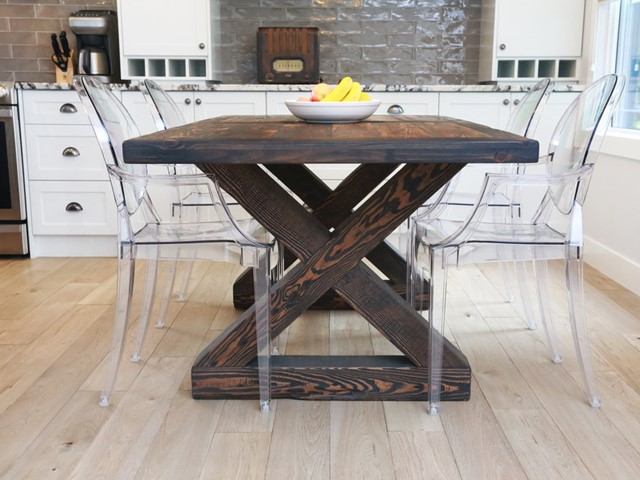 Dark wood dining table with X base, clear chairs, bowl of bananas in kitchen.