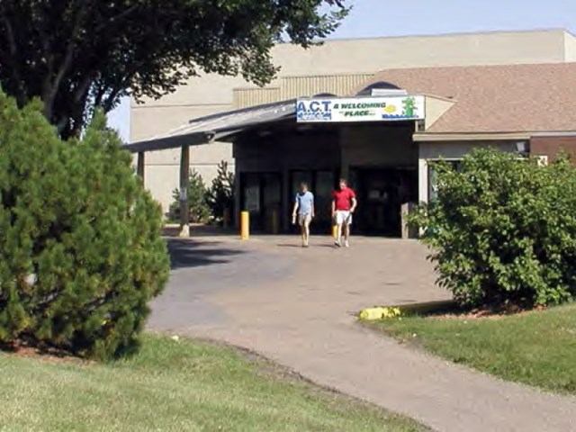 Entrance to ACT Aquatic & Recreation Centre with pathway, trees, and clear skies.