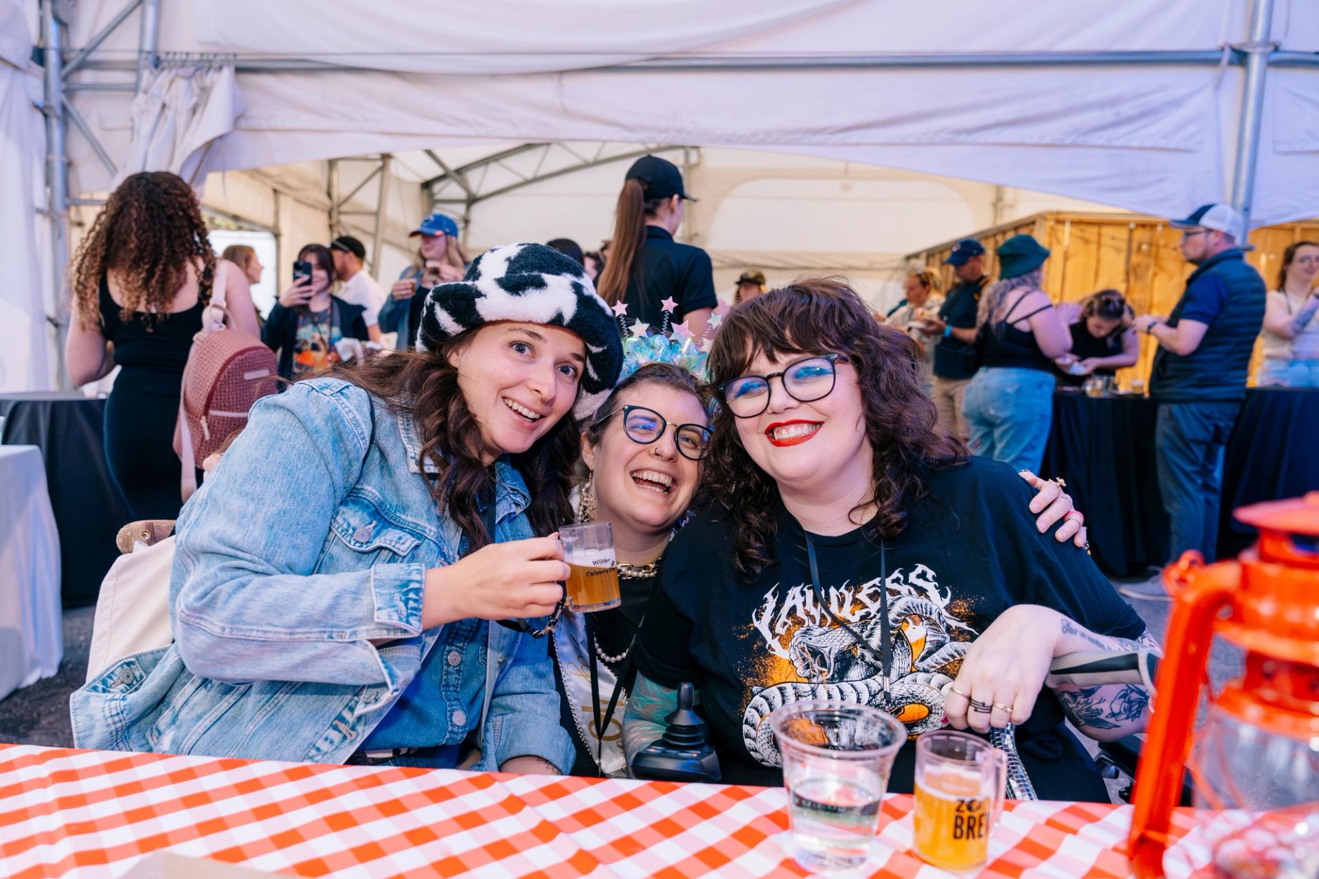 Friends pose with drinks at a picnic table during a lively Zoo Brew event.