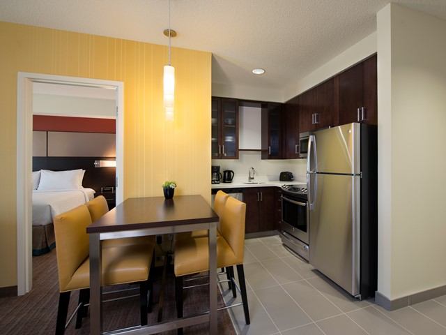 : Stainless steel appliances and dining table with yellow chairs in suite kitchen