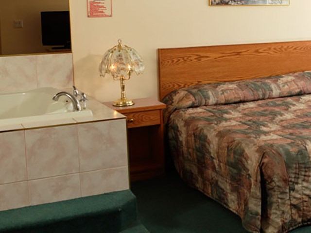 Motel room with a large bed and an in-room jacuzzi tub.