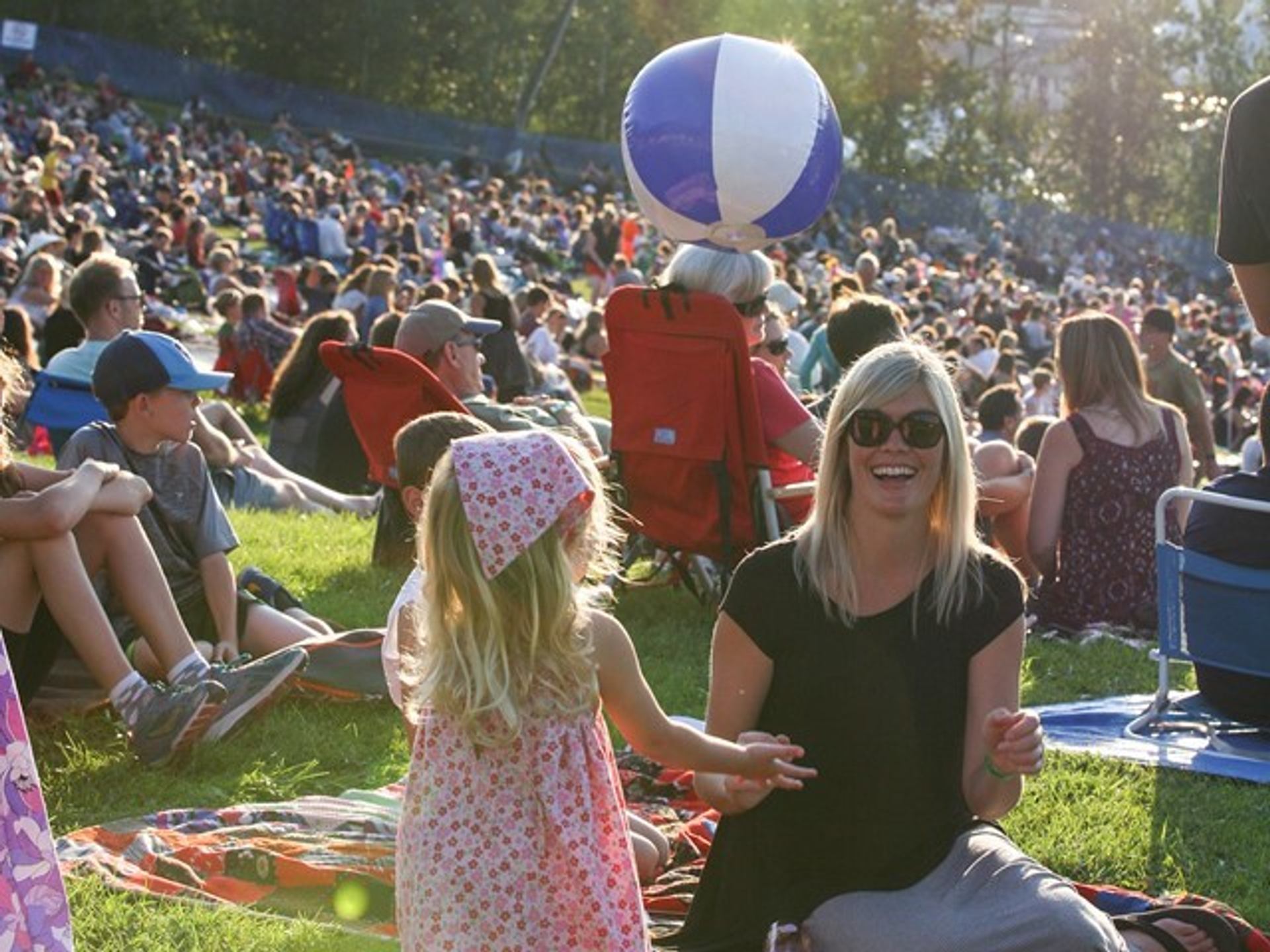 Child and adult enjoying a sunny day at a crowded outdoor music festival
