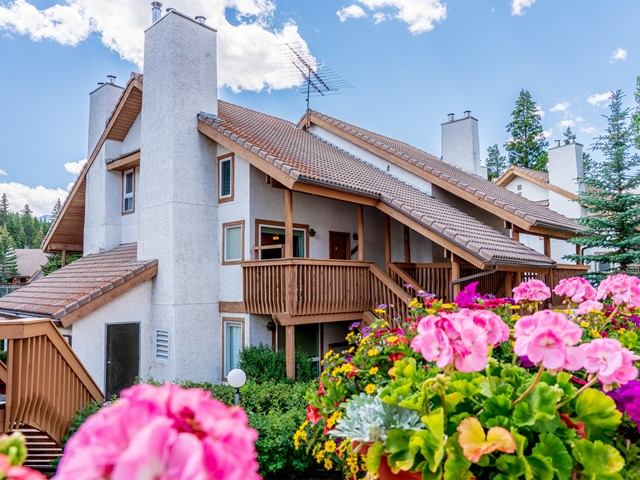 Rustic resort with balconies, flowers, and mountain scenery.