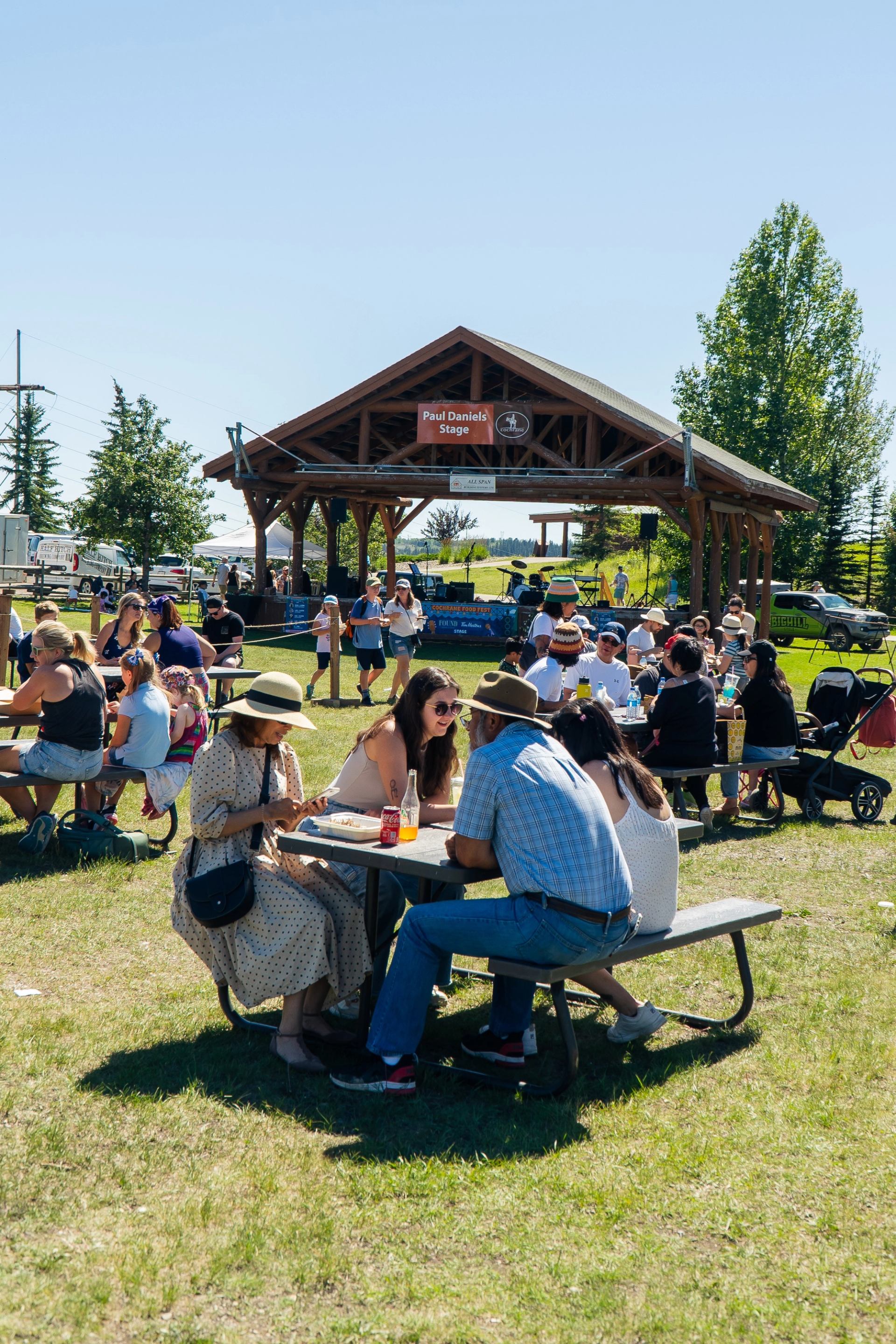 groups of people sat at picnic tables enjoying food.