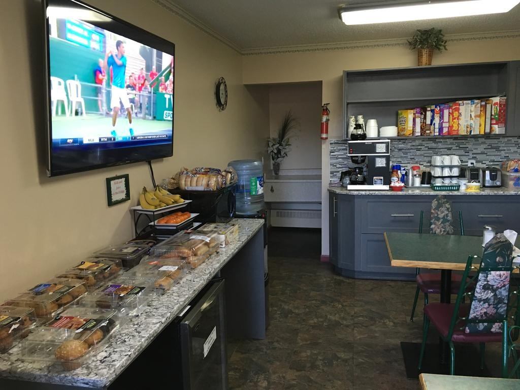 Hotel breakfast area with coffee machine, pastries display, vending TV, and counter items.