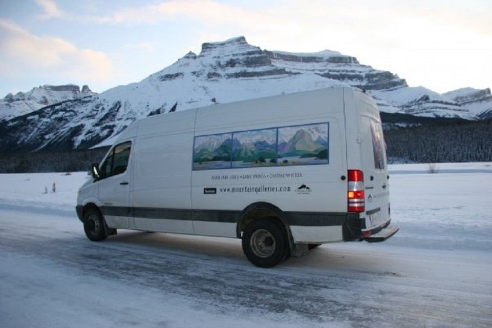 Mountain Galleries van on snowy road with mountain mural and peaks behind.