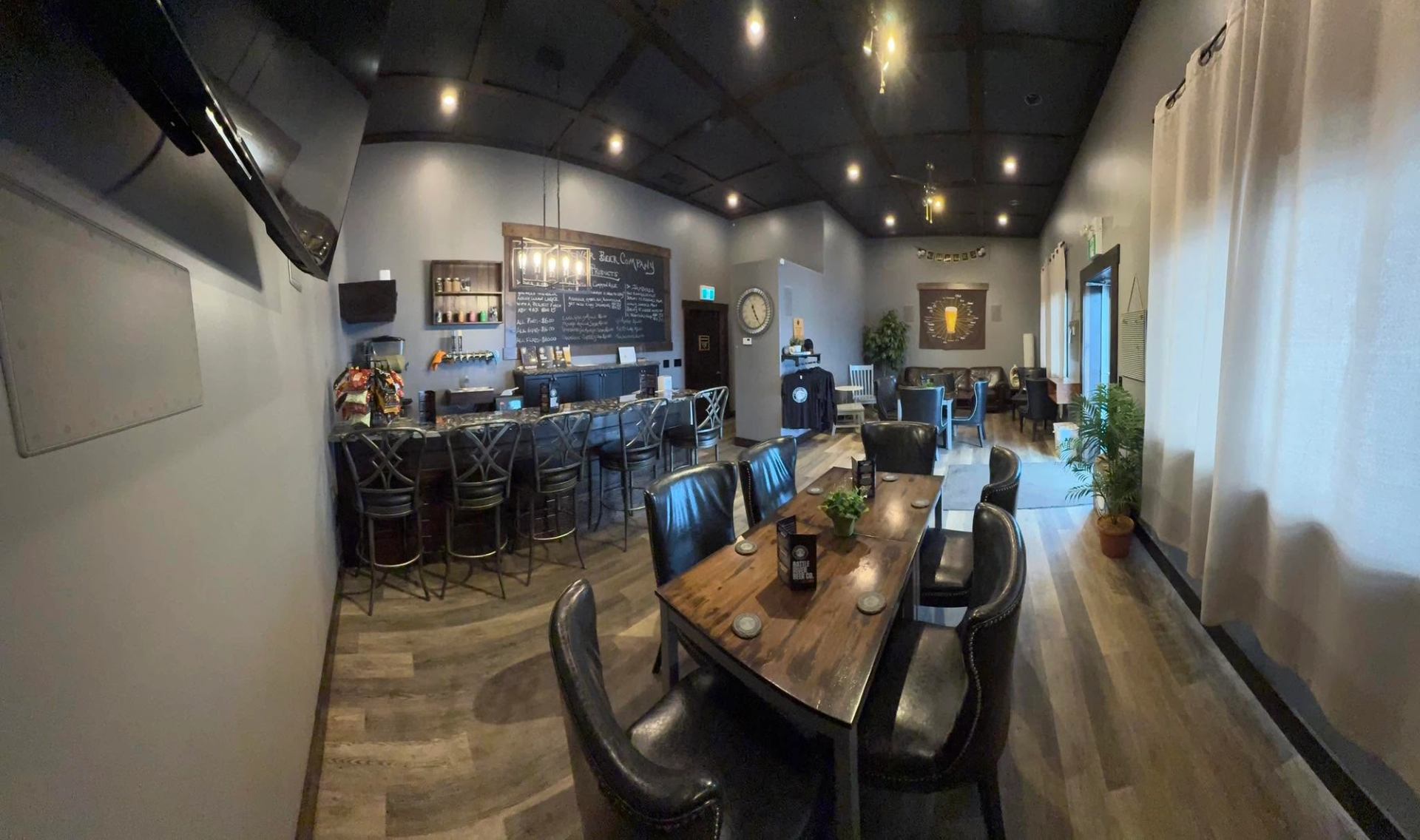 A cozy taproom features wooden tables, leather chairs, a bar area, and a brewery beer menu board.