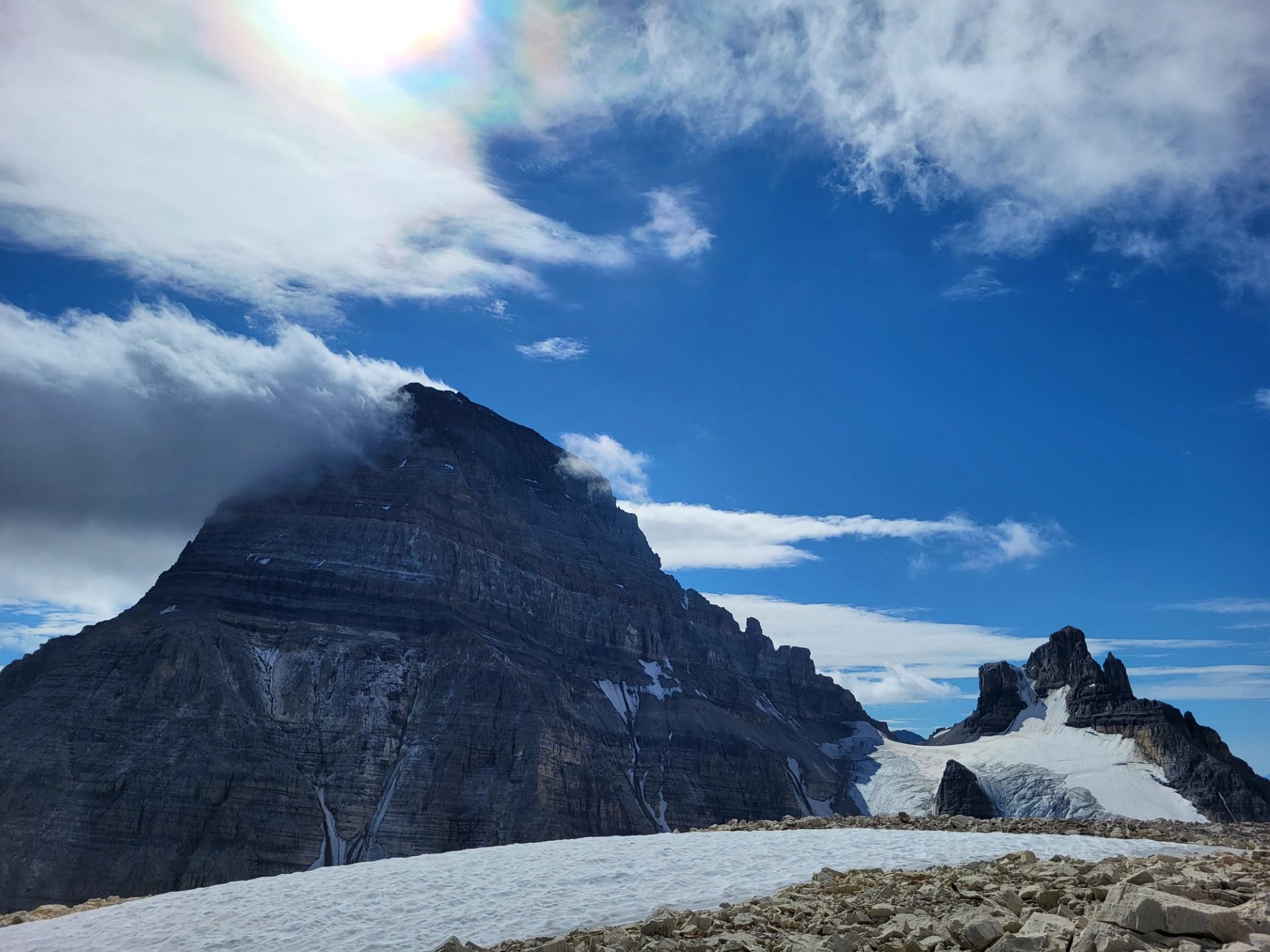 Rugged mountain peaks under a bright sky with snow and rocky terrain.