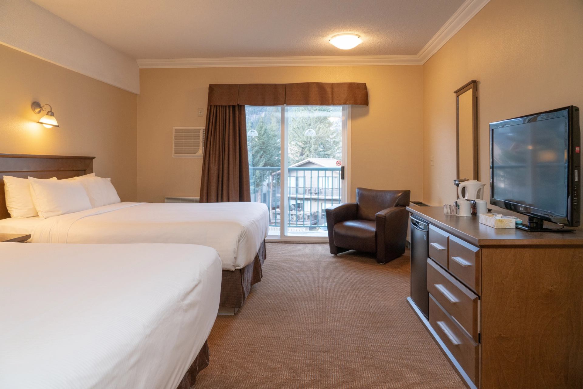 Cozy hotel room with two beds, balcony access, and modern amenities.
