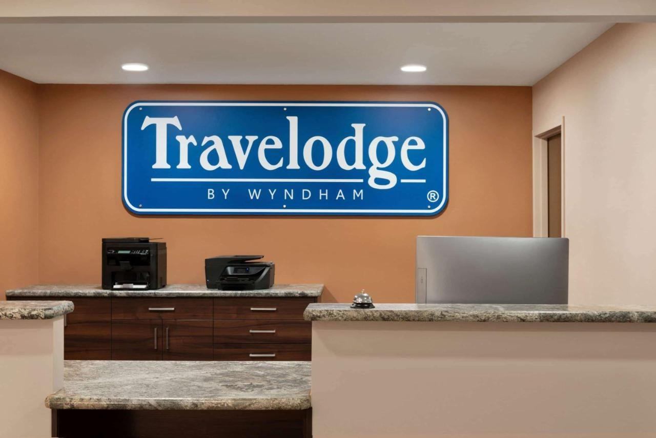 Travelodge front desk with blue logo sign and office equipment.