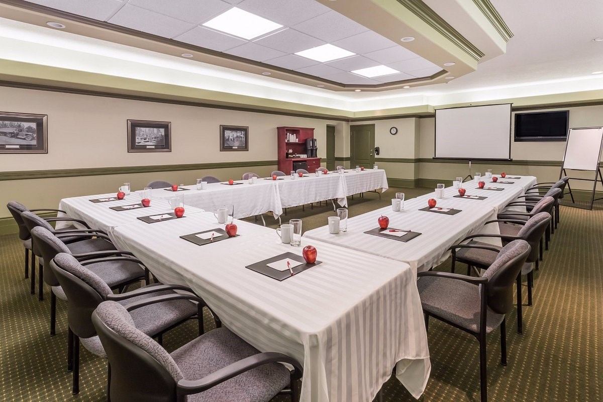 U-shaped meeting setup with notepads, apples, and projector at Ramada Hinton.
