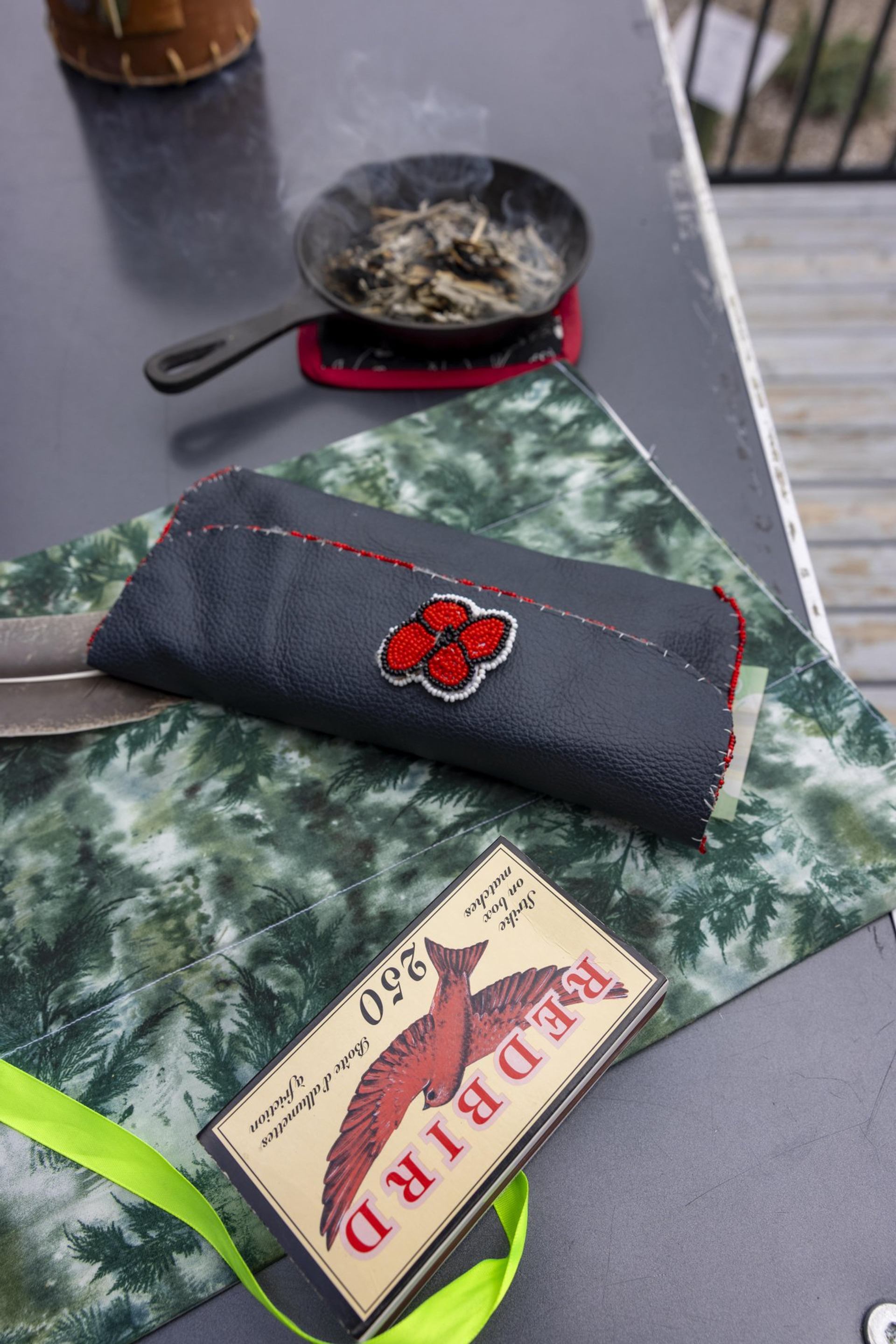 A smudge table with cast iron frying pan for smudge, feather,wooden matches, pouch of tobacco