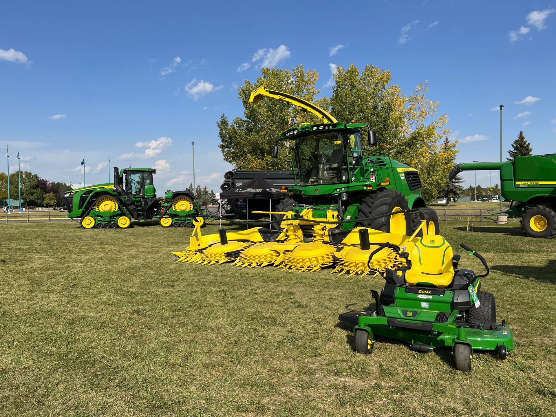 Large green farm equipment displayed on open grass at the festival.