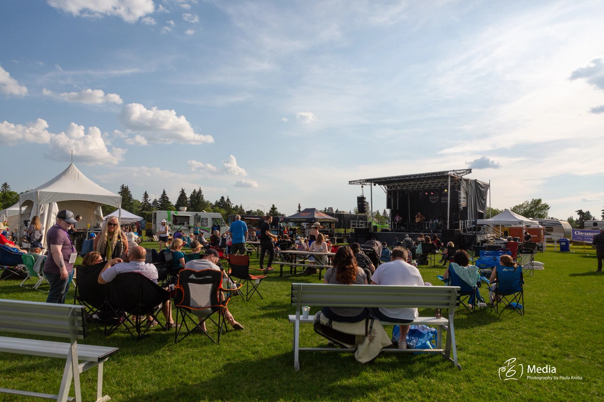 Crowd seated on lawn chairs facing a stage at an outdoor music festival.