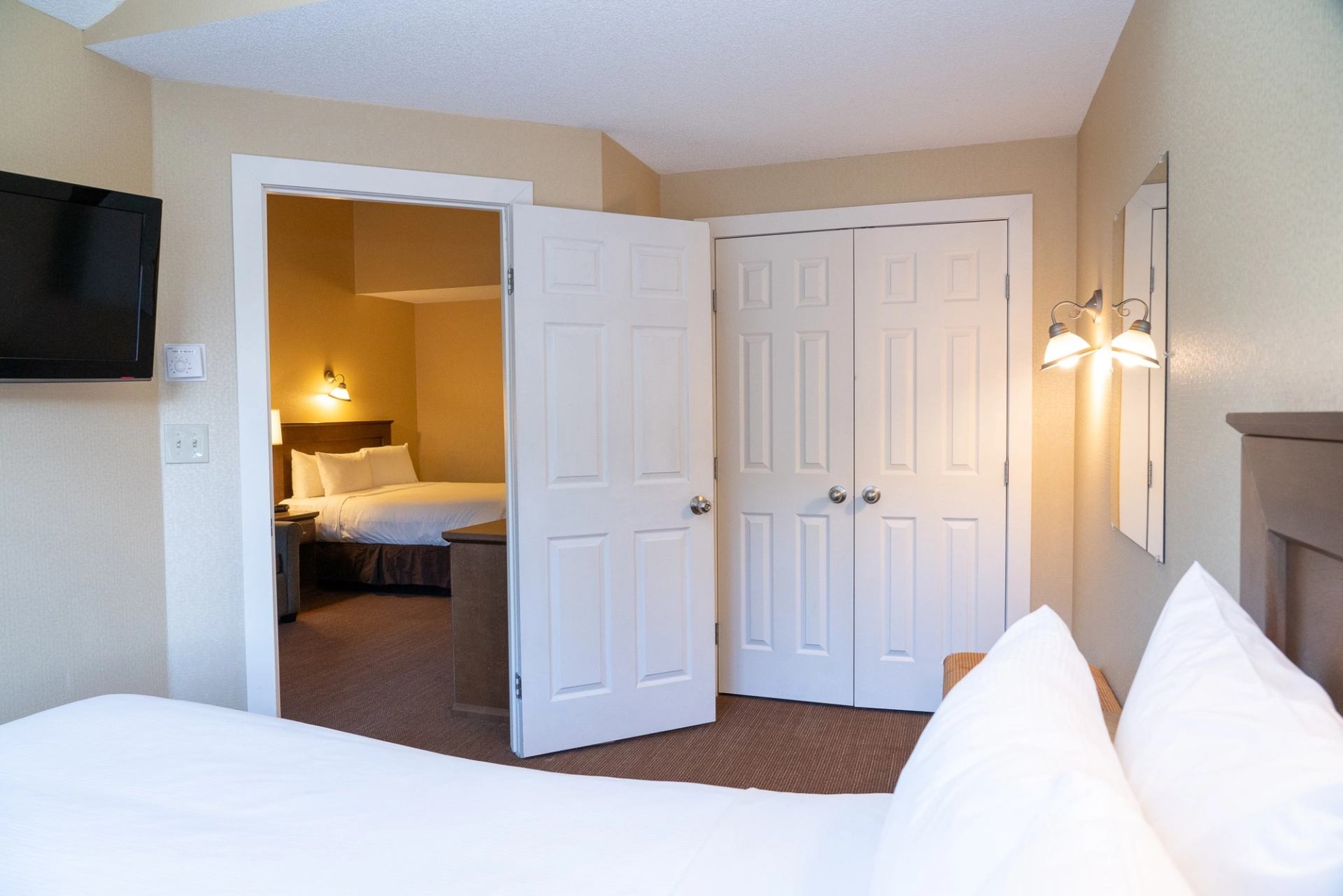 Hotel suite with two beds, warm lighting, and connecting room layout.