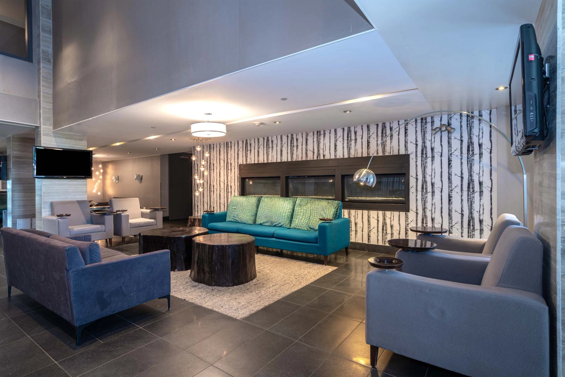 Contemporary hotel lounge with sofas, statement lighting, and a modern fireplace.