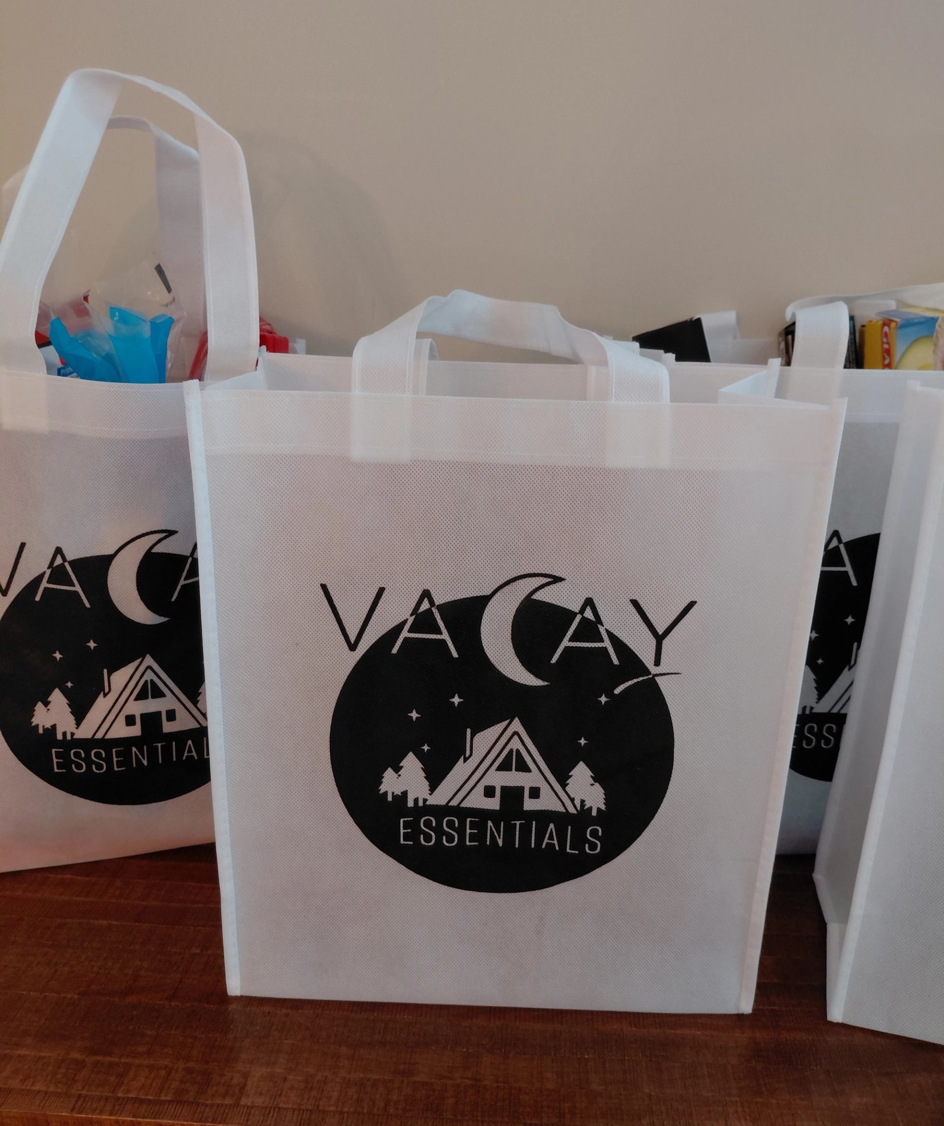 Three tote bags labeled “Vacay Essentials” filled with colorful travel items.