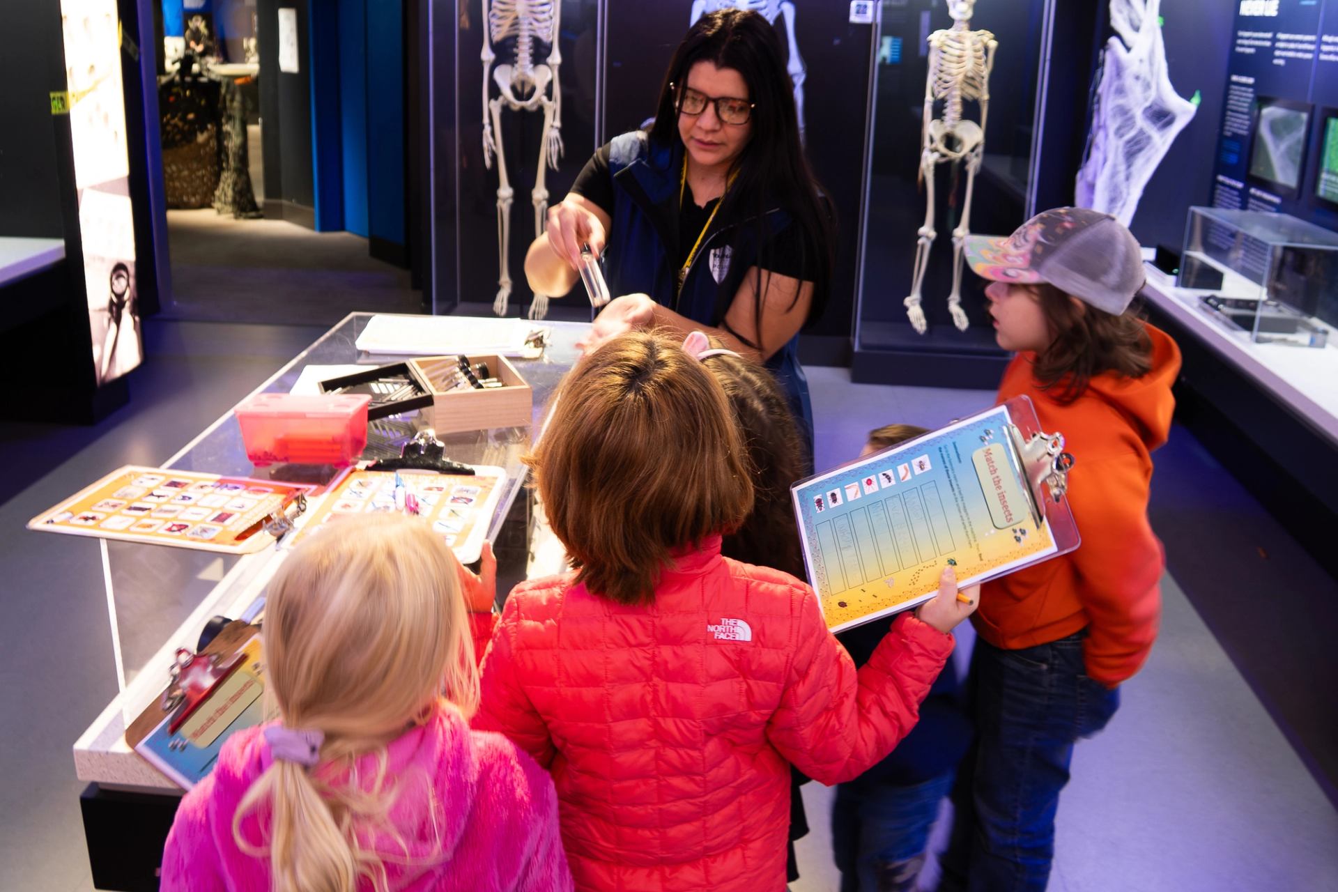  Children at a table with forensic tools and charts during an interactive exhibit
