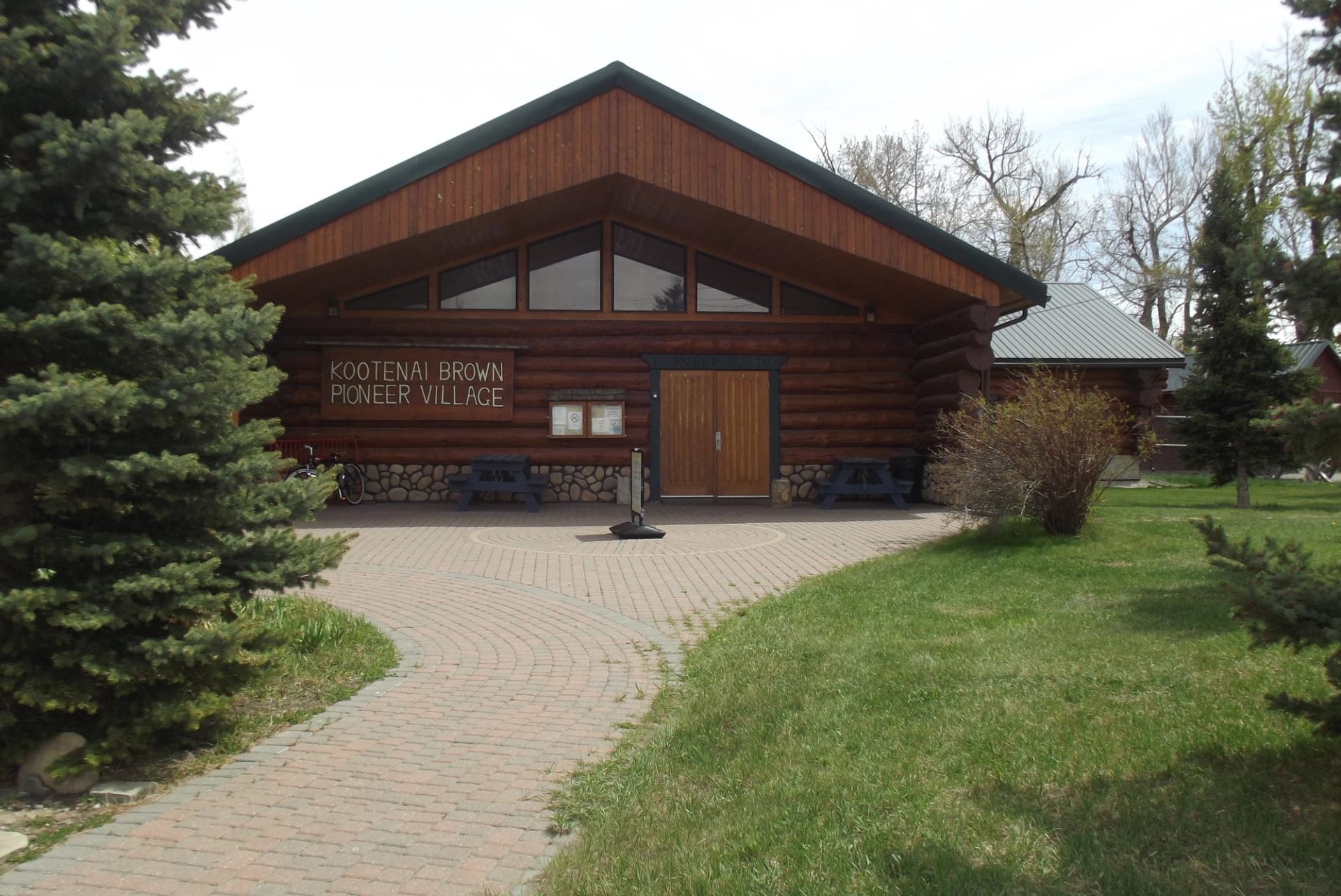 Log cabin visitor center with green roof and trees at Pincher Creek VIC.