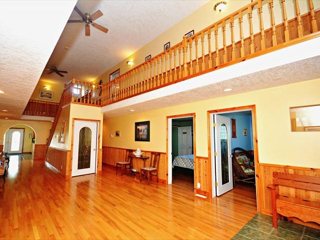 Spacious home interior with wood floors, staircase, cozy seating, and doors leading to other rooms.