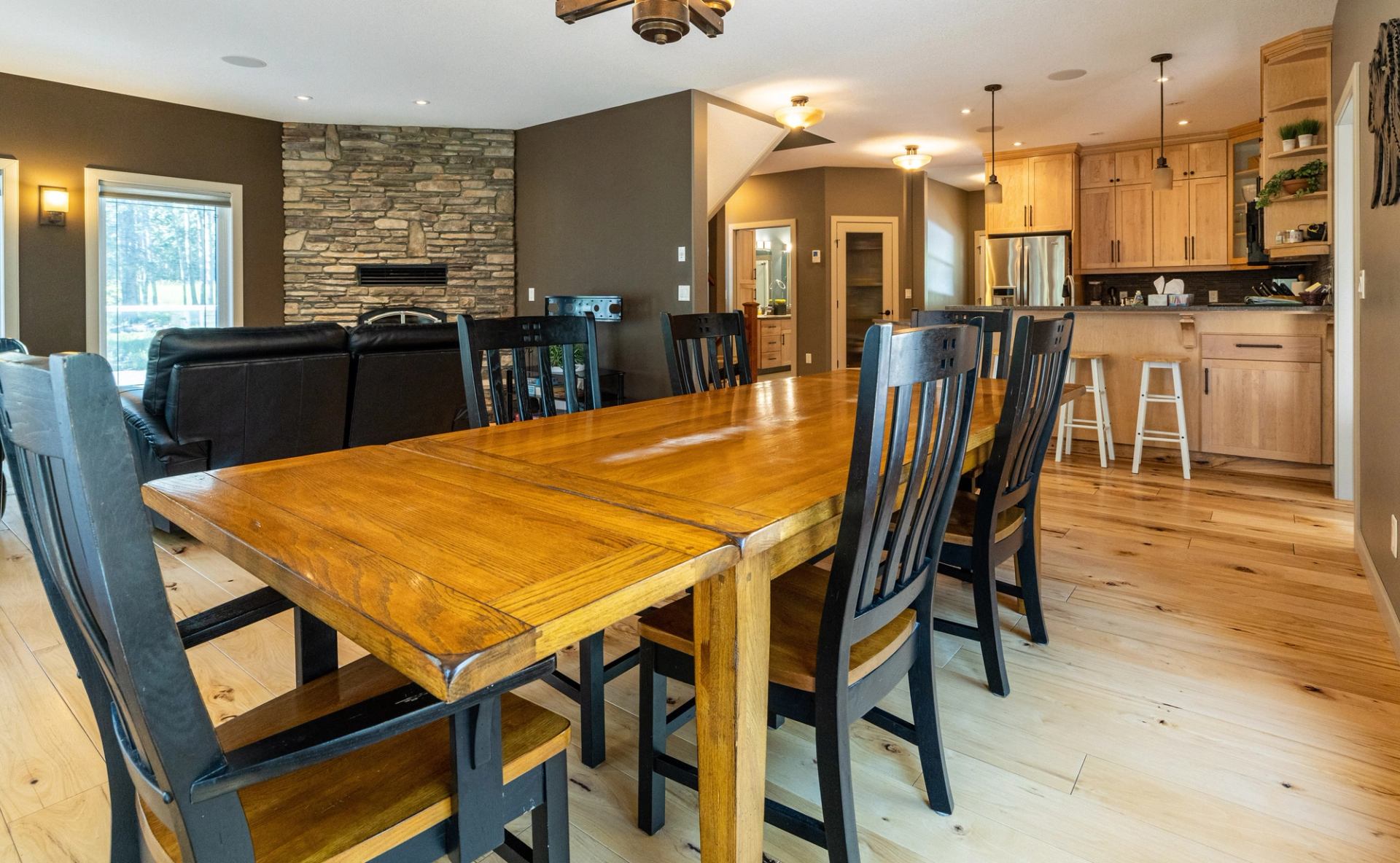 Dining room with wood table, black chairs, and stone fireplace.