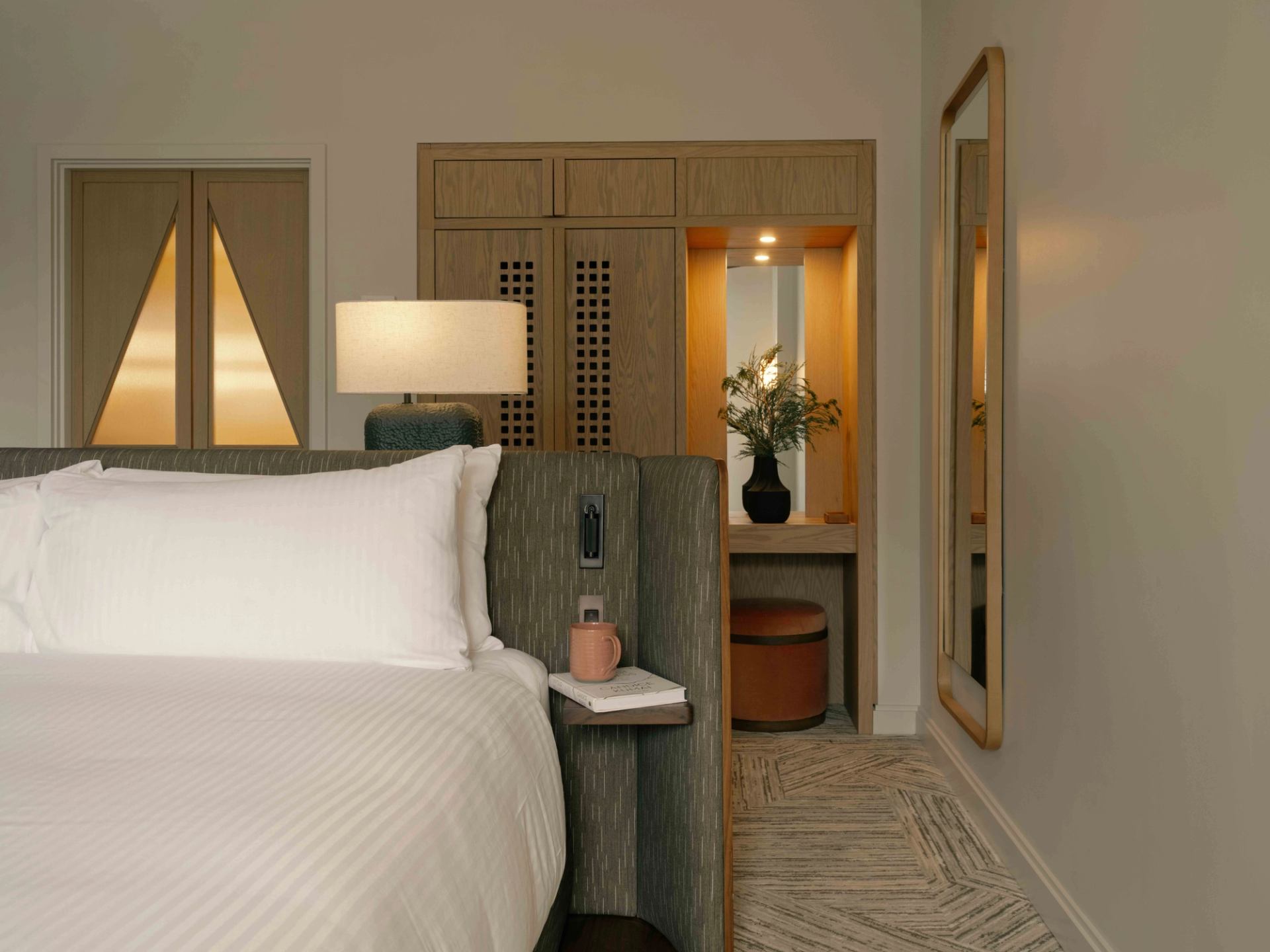 Elegant hotel guest room with plush bed, warm wood accents, bedside lighting, and a cozy seating nook at Rimrock Banff.