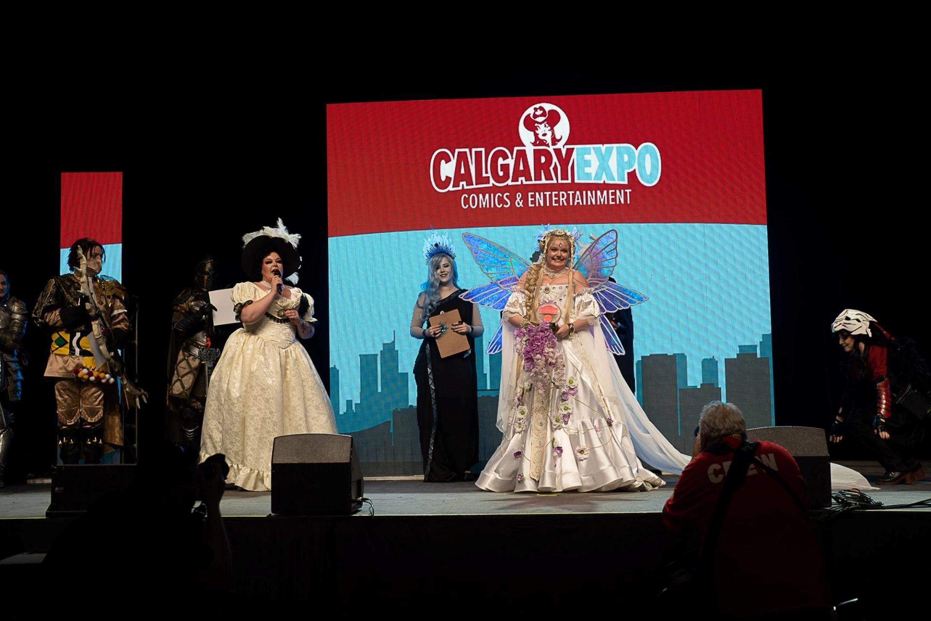 Cosplayers in elaborate fantasy costumes stand on stage at Calgary Comic and Entertainment Expo.