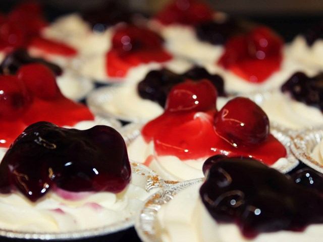 Mini gluten-free dessert cups topped with whipped cream and fruit preserves.