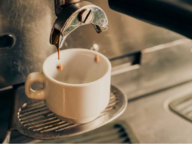 Espresso dripping into a white cup from a café machine.